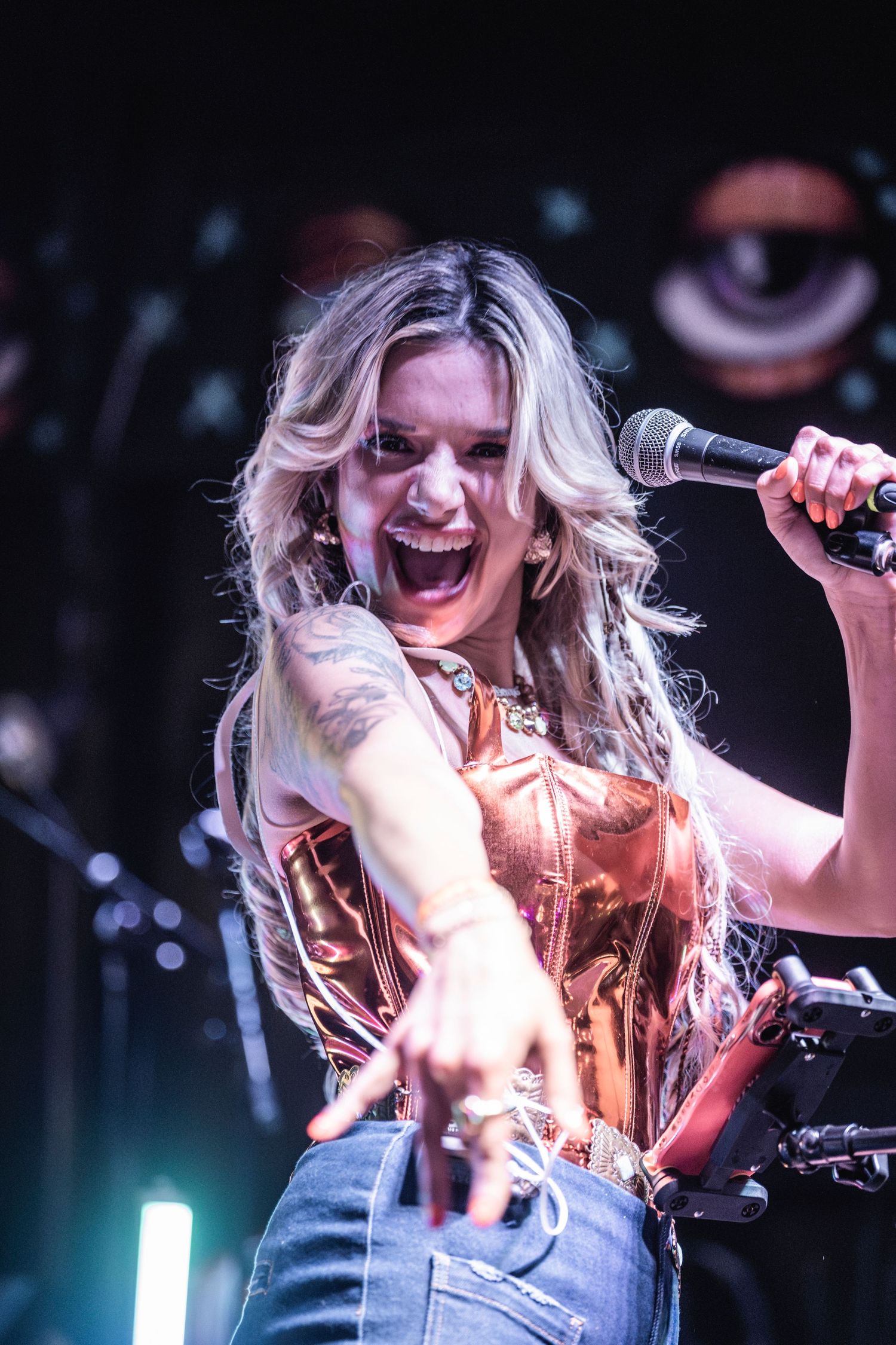 A series of energetic performance shots showing a singer with wavy blonde hair singing and performing on stage with a microphone.