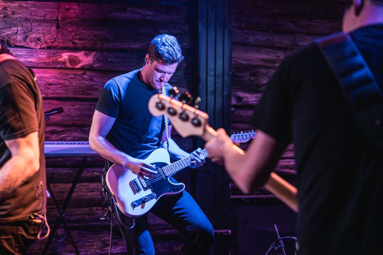 Guitarist performing on stage in blue lighting at an intimate venue.