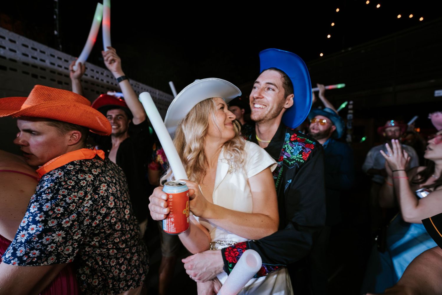 Party attendees celebrating with glow sticks at outdoor nighttime event.