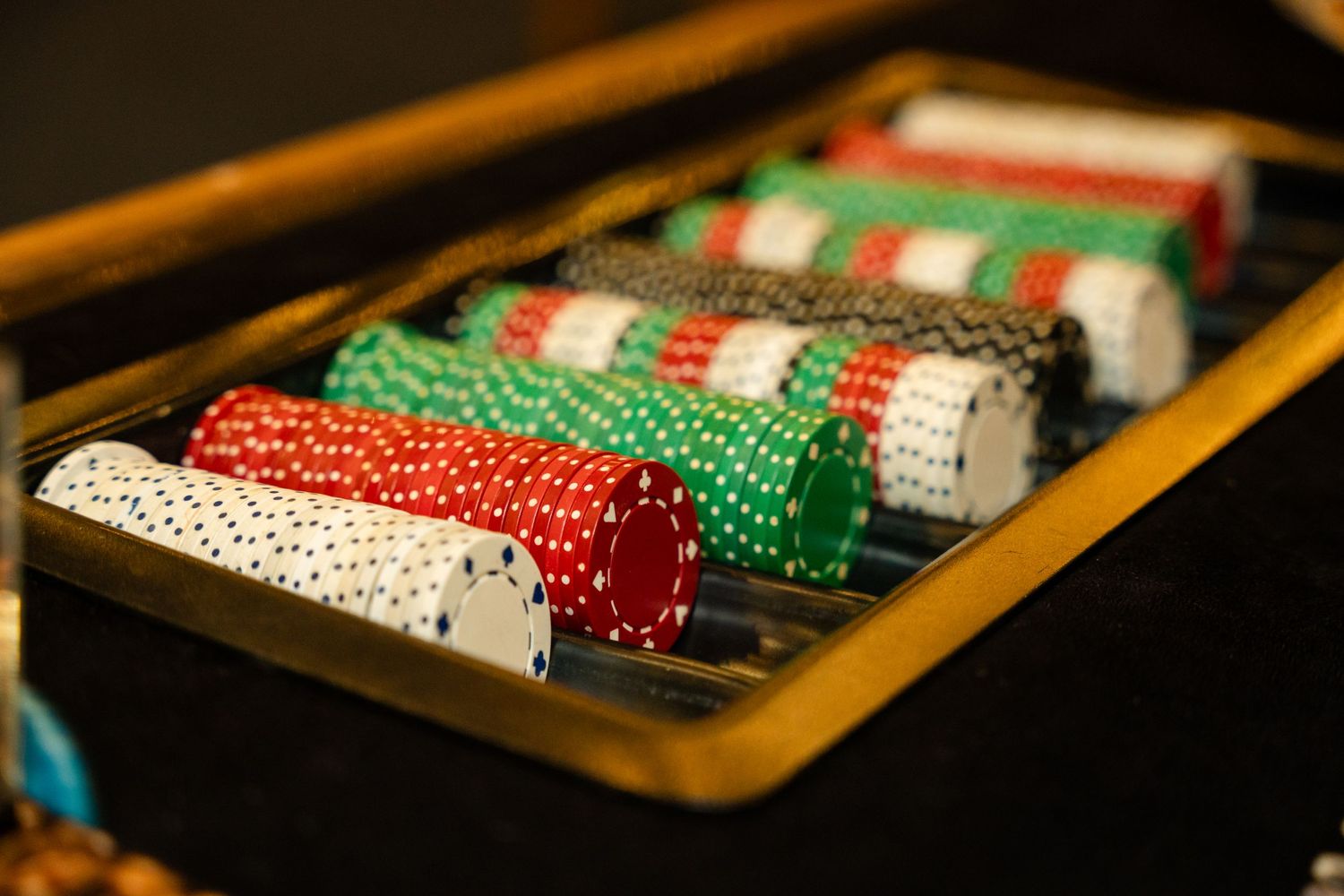 Close-up of colorful poker chips stacked in rows inside a wooden tray.