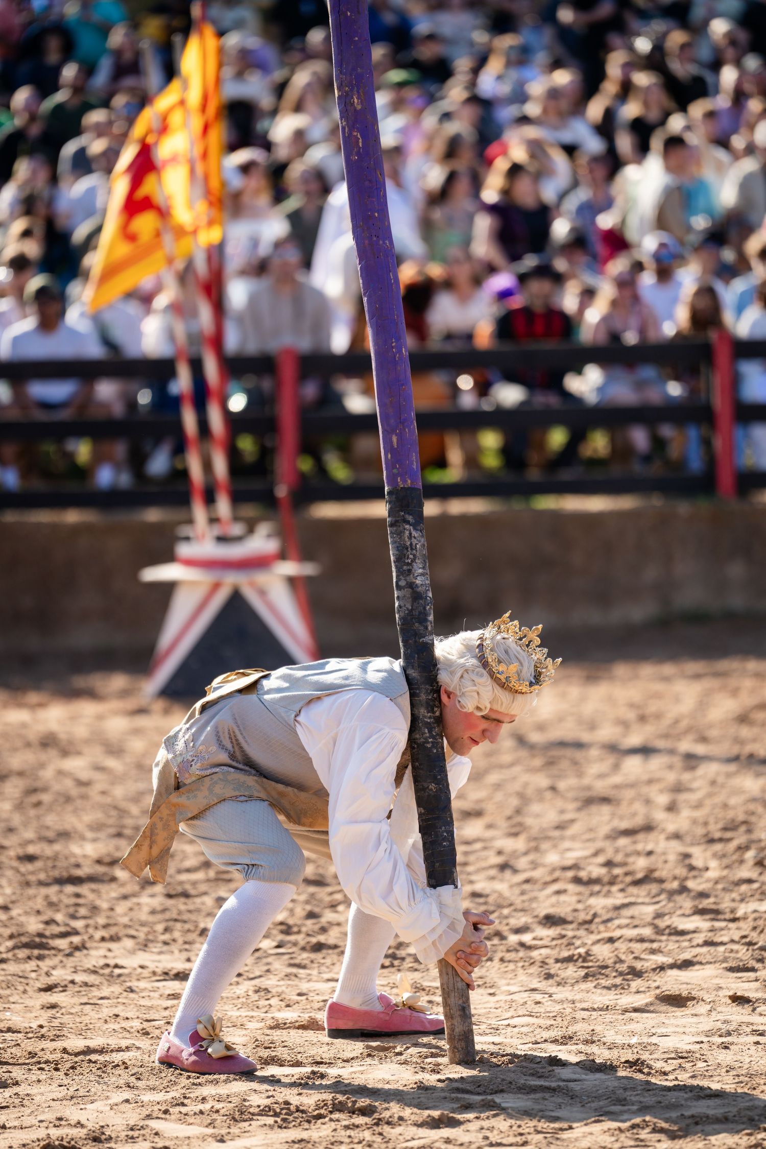 A sequence showing a person in white clothing attempting to limbo dance under a low purple bar in a sandy arena.