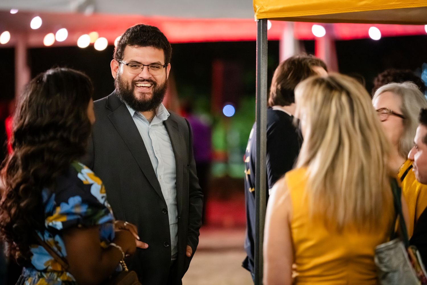 A group of people networking and socializing at a professional business event in a dimly lit venue.