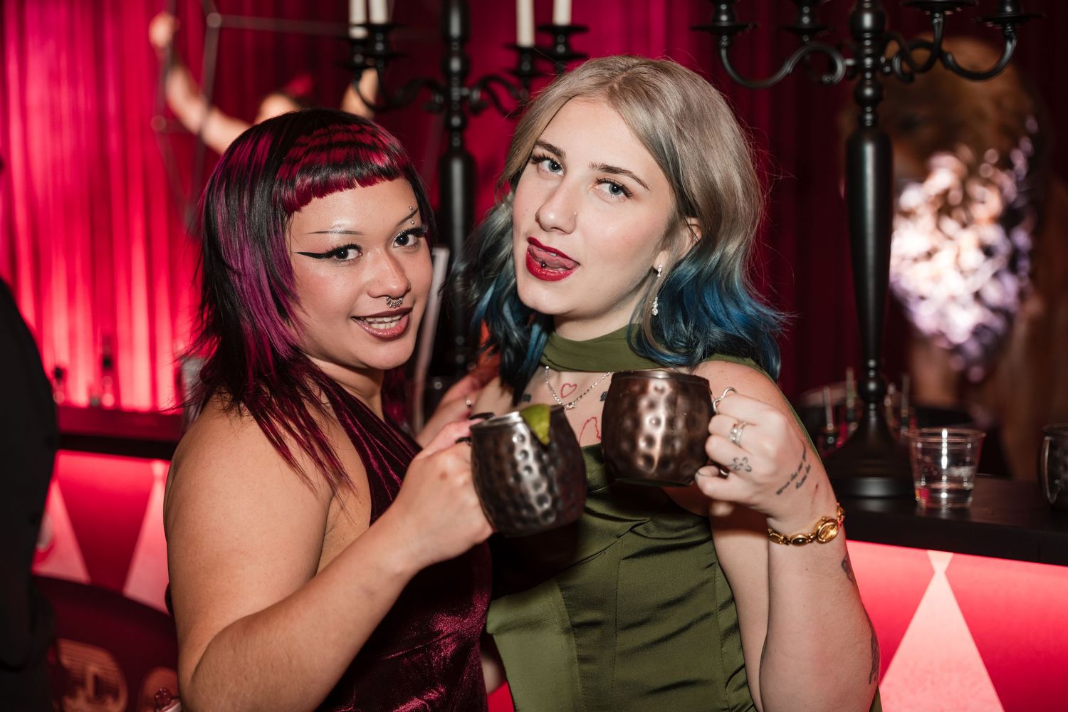 People enjoying themselves at a nightclub with red lighting and decorative elements in the background.