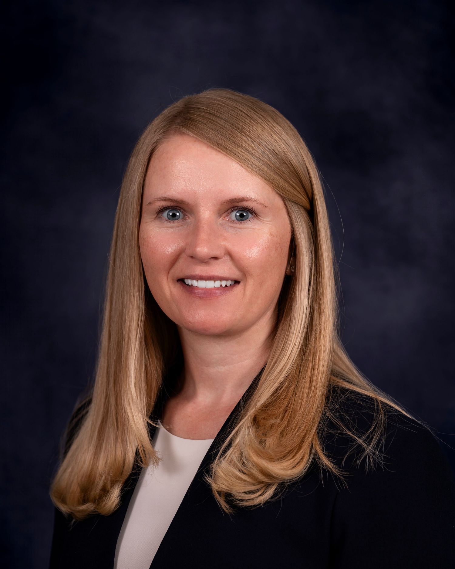 Professional headshot series of a woman in business attire with blonde hair against a dark background.