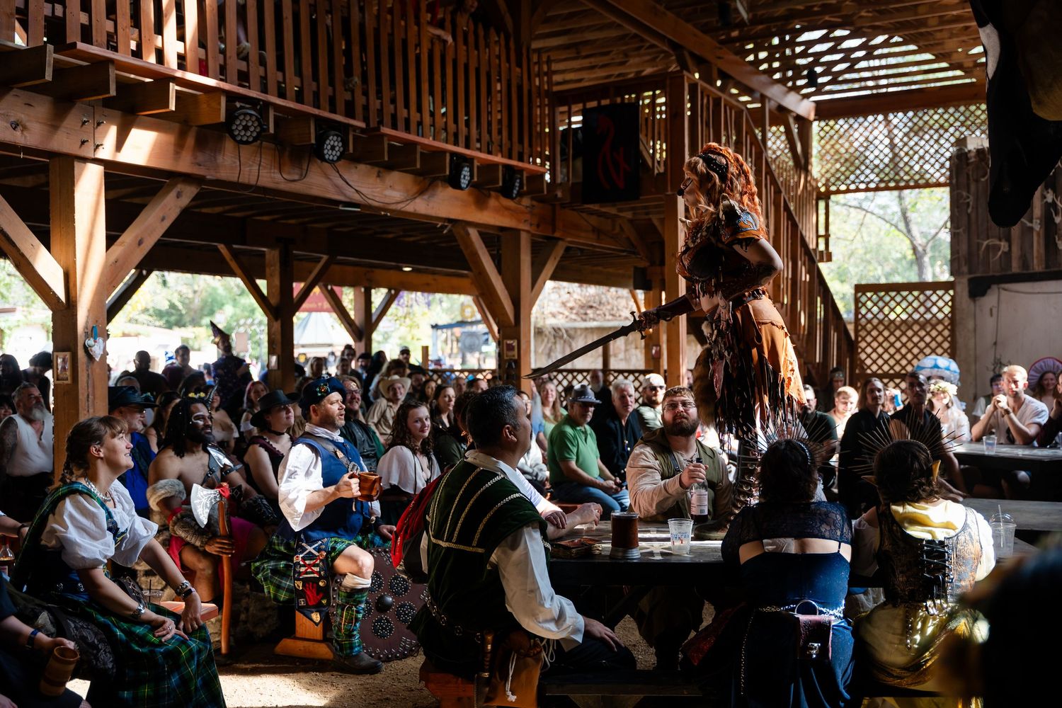 A rustic wooden barn venue filled with guests seated at long tables for a wedding reception celebration.