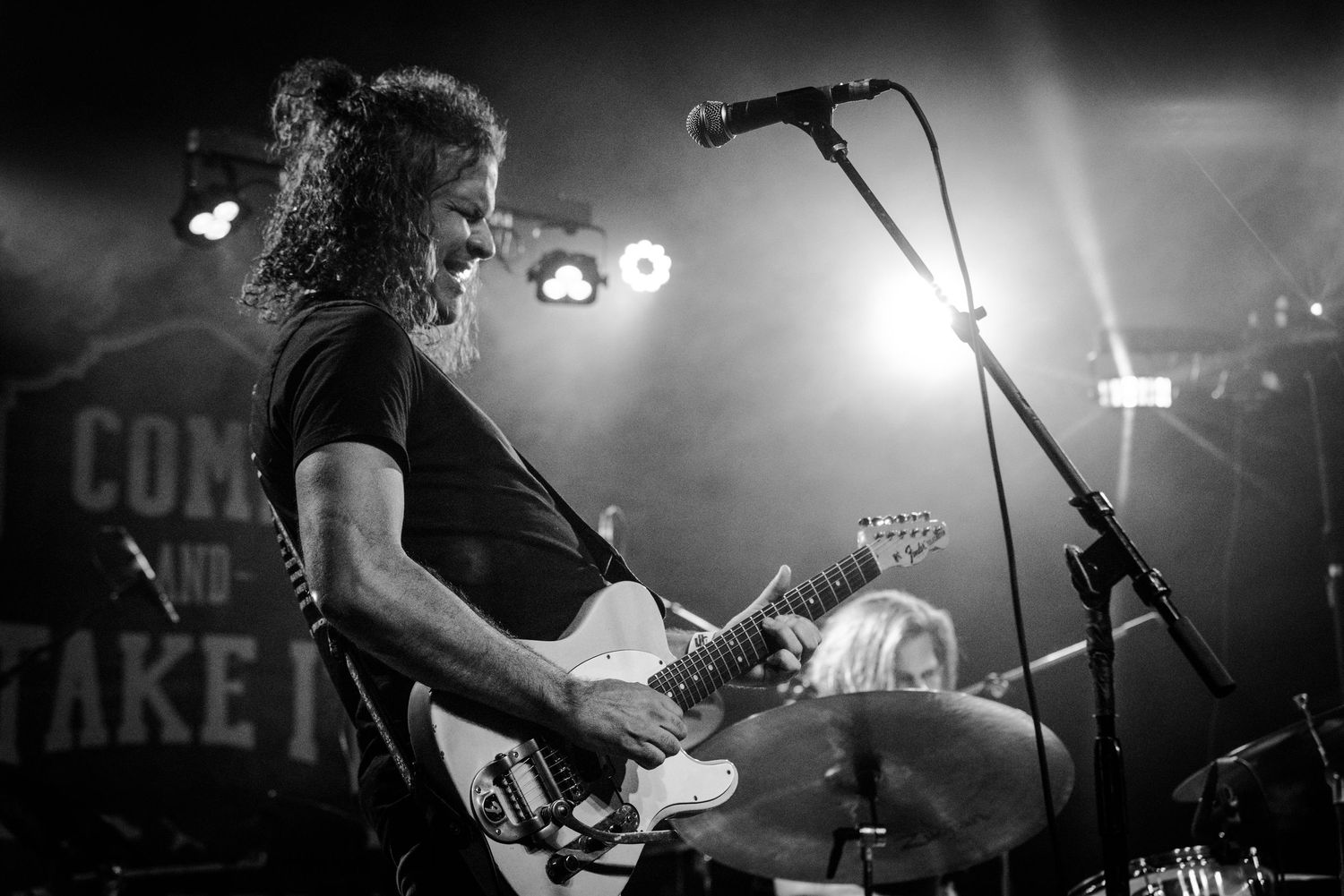 Musicians perform on stage with electric guitars and dramatic lighting during a rock concert.