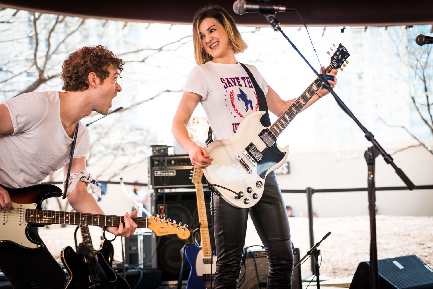 Musicians perform energetically on stage with guitars during an outdoor concert performance.