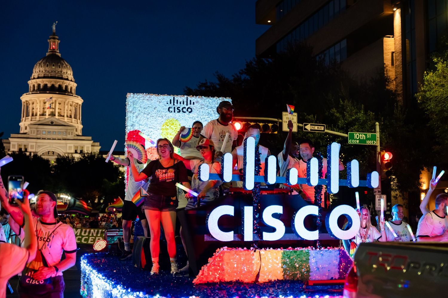 Cisco-branded parade float with colorful lights at night near a capitol building during a festive event.