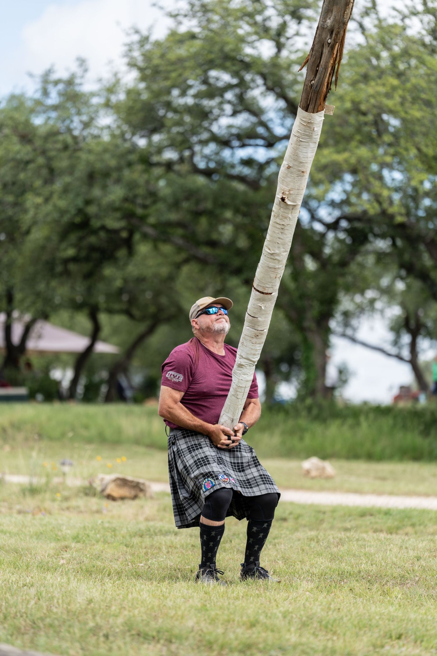 Man in kilt tossing caber at Highland Games competition outdoors.