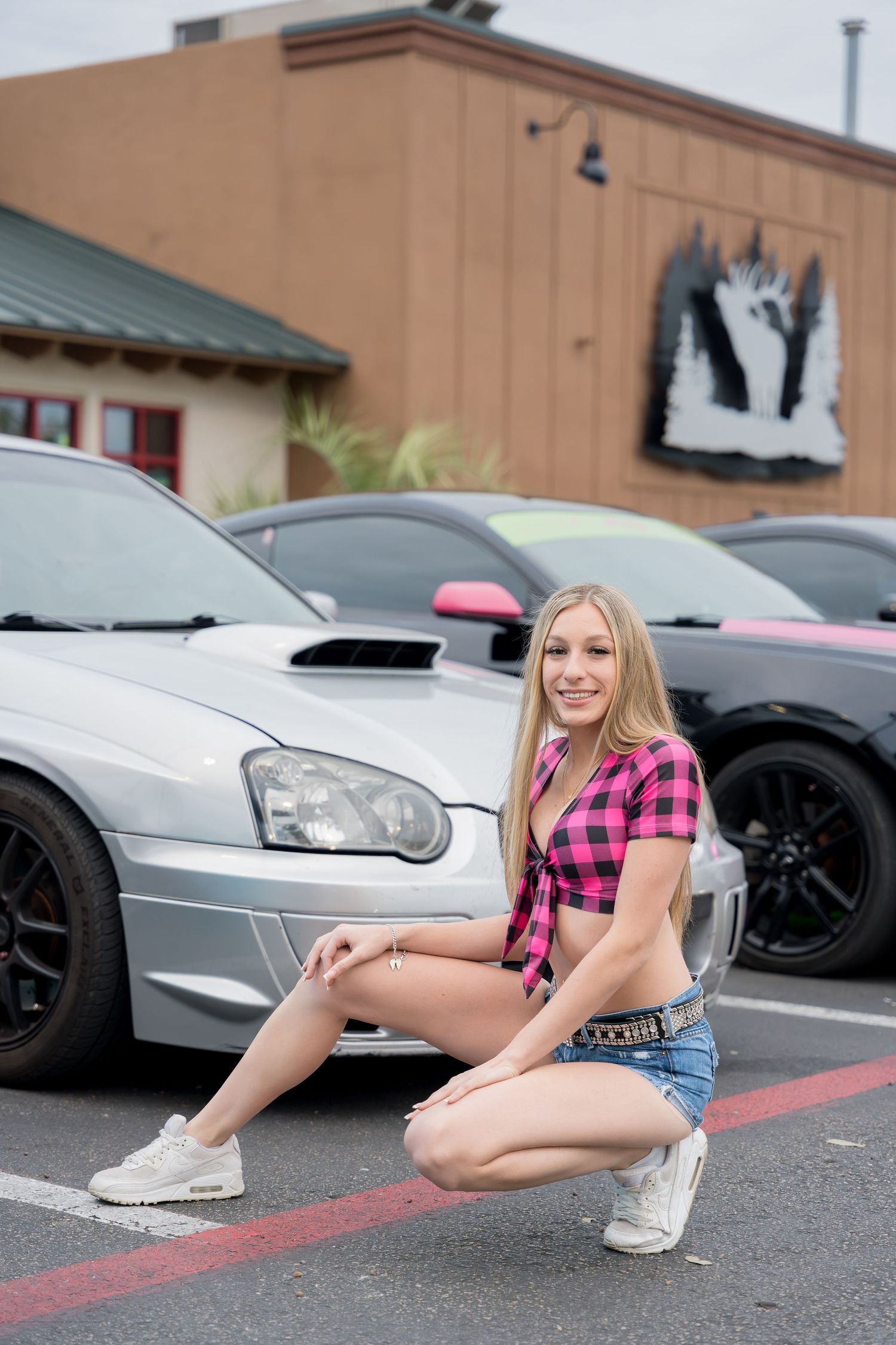 Casual automotive photoshoot featuring pink plaid top and denim shorts by silver car.
