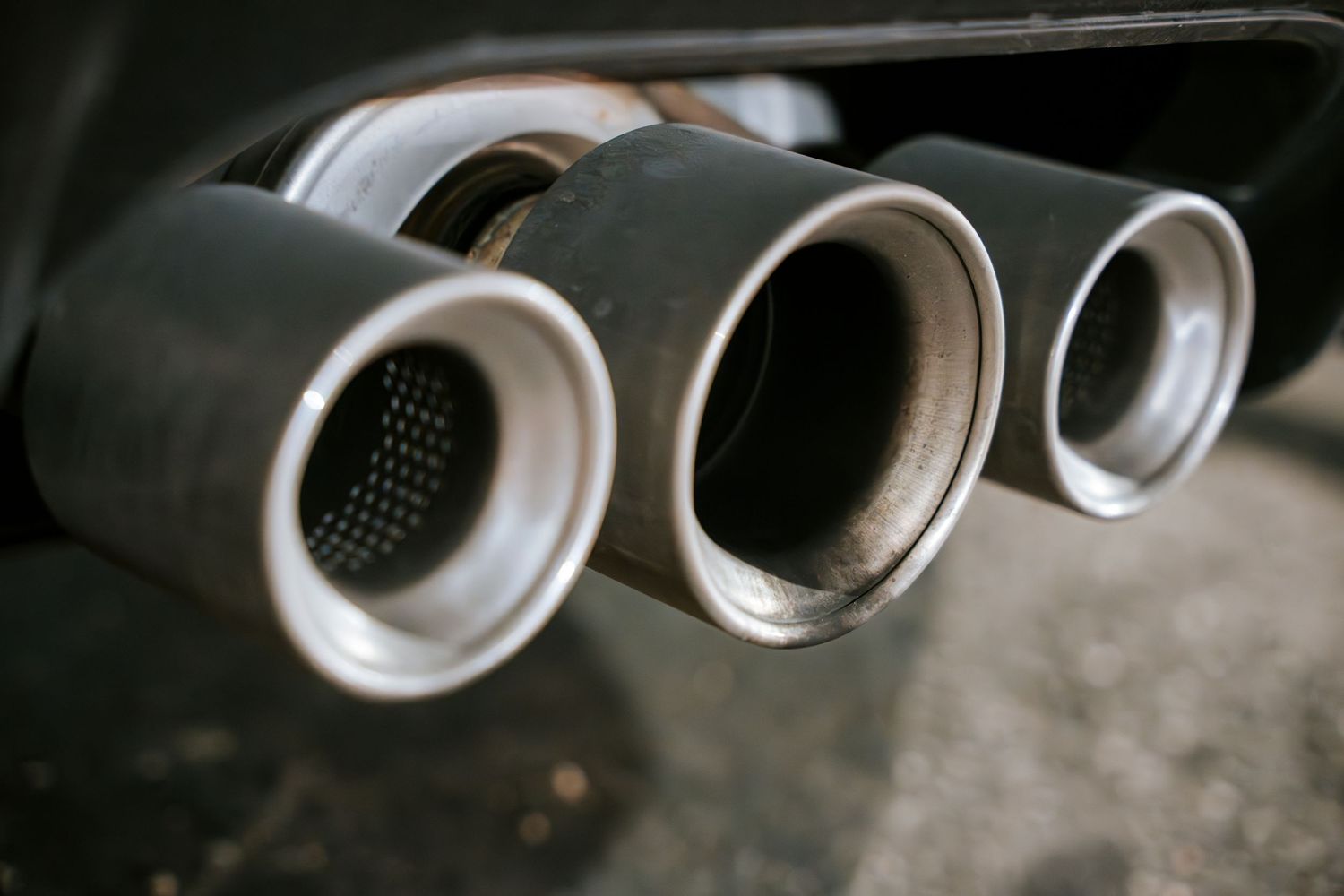 Close-up detail shot of three silver exhaust tips on a performance car.