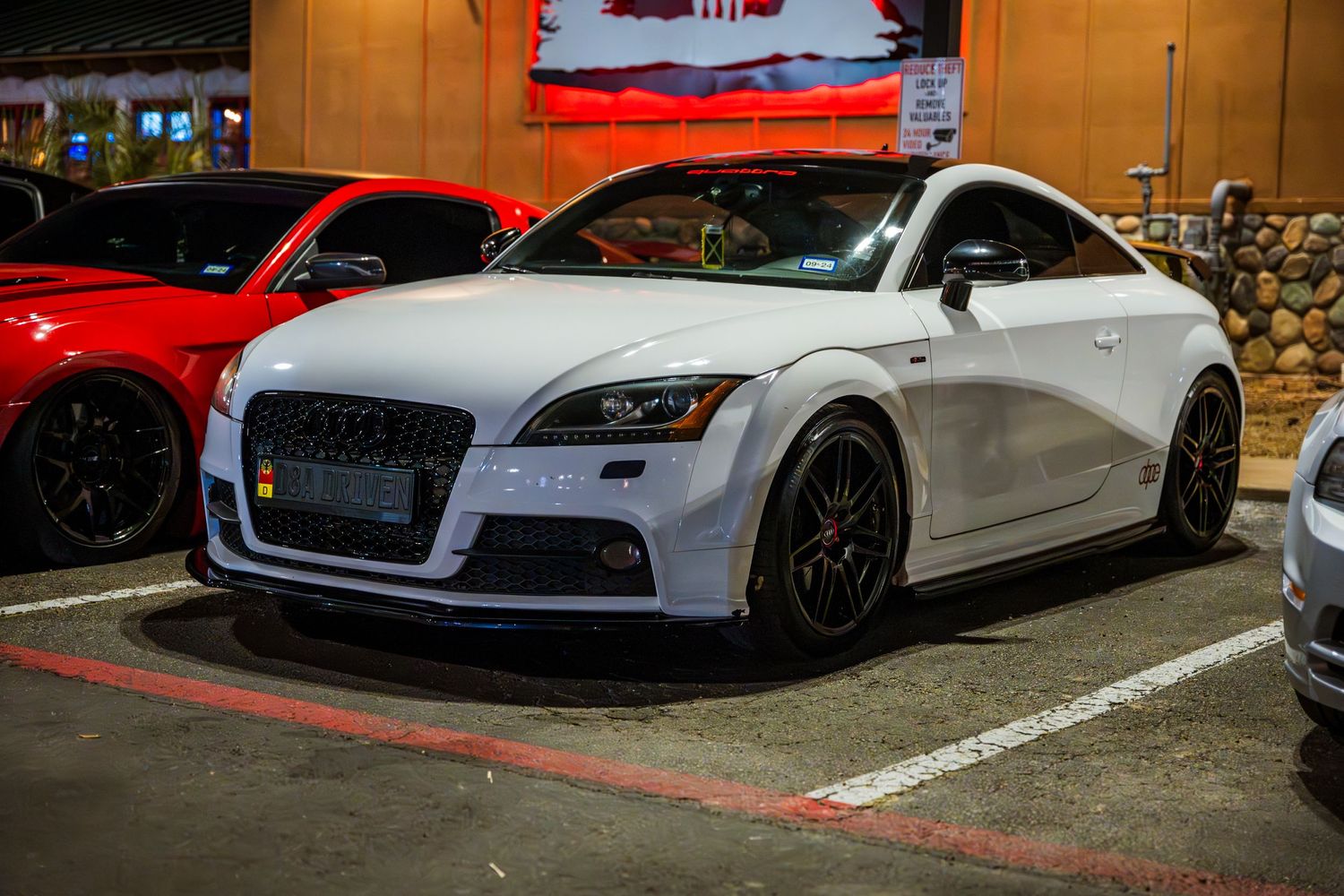Modified white Audi TT with aftermarket wheels parked at night.