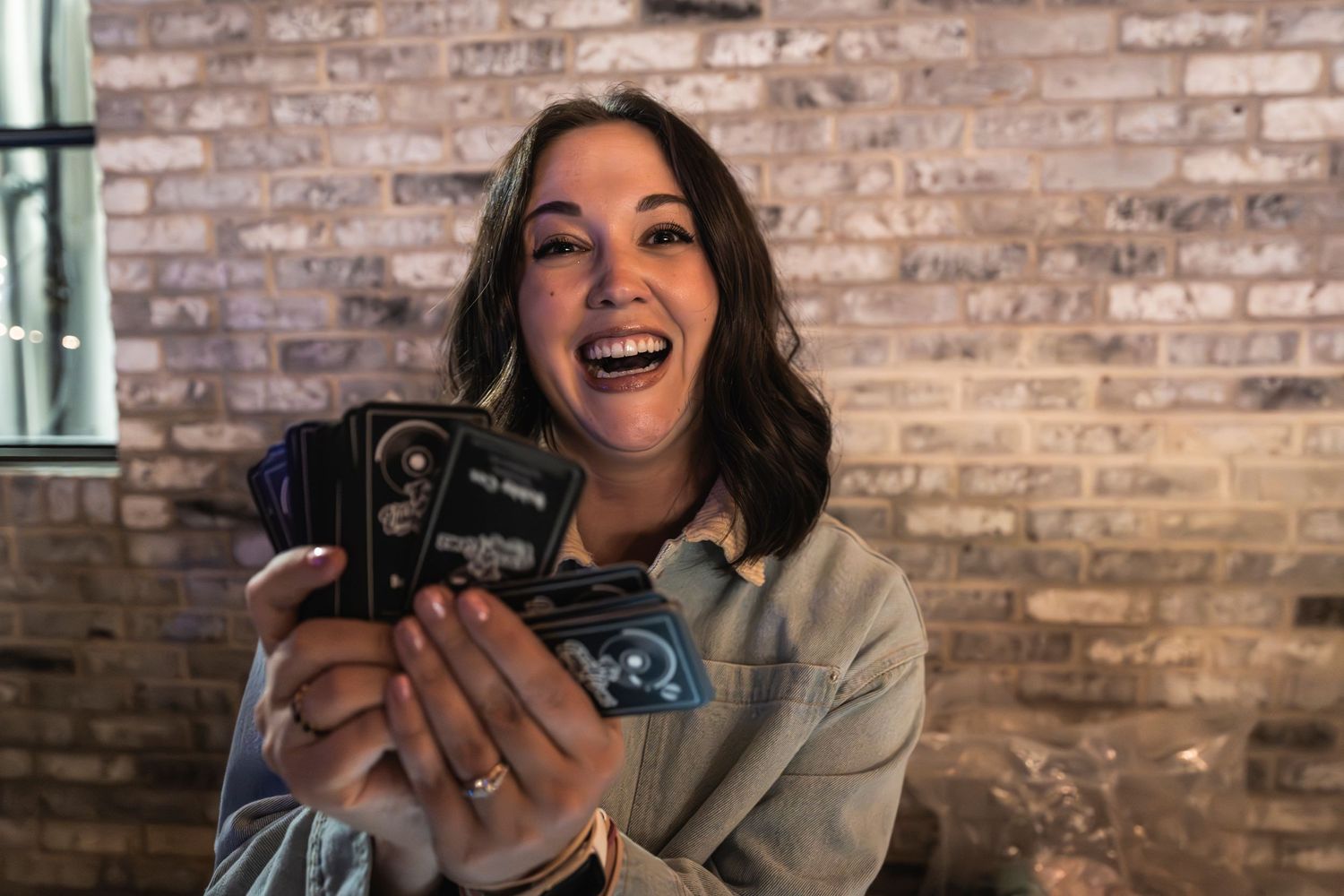 Enthusiastic photographer holding a vintage camera against a brick wall background.