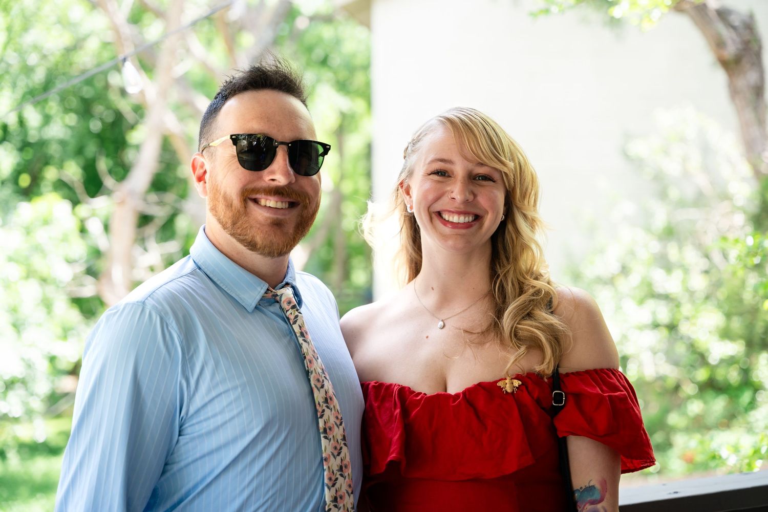 Wedding guests in summer attire pose together at an outdoor event.