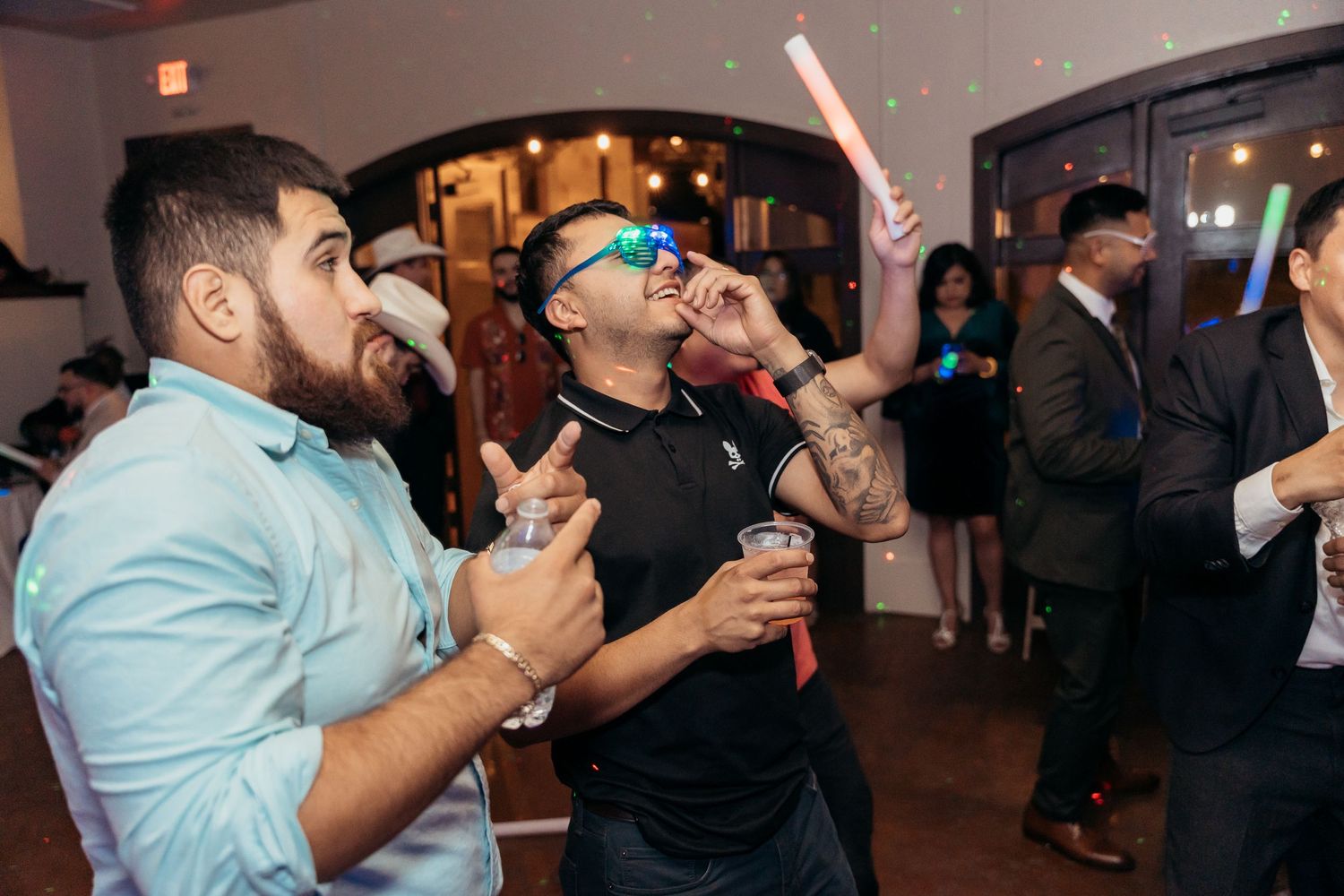 Party guests energetically dancing and singing at an indoor celebration event.