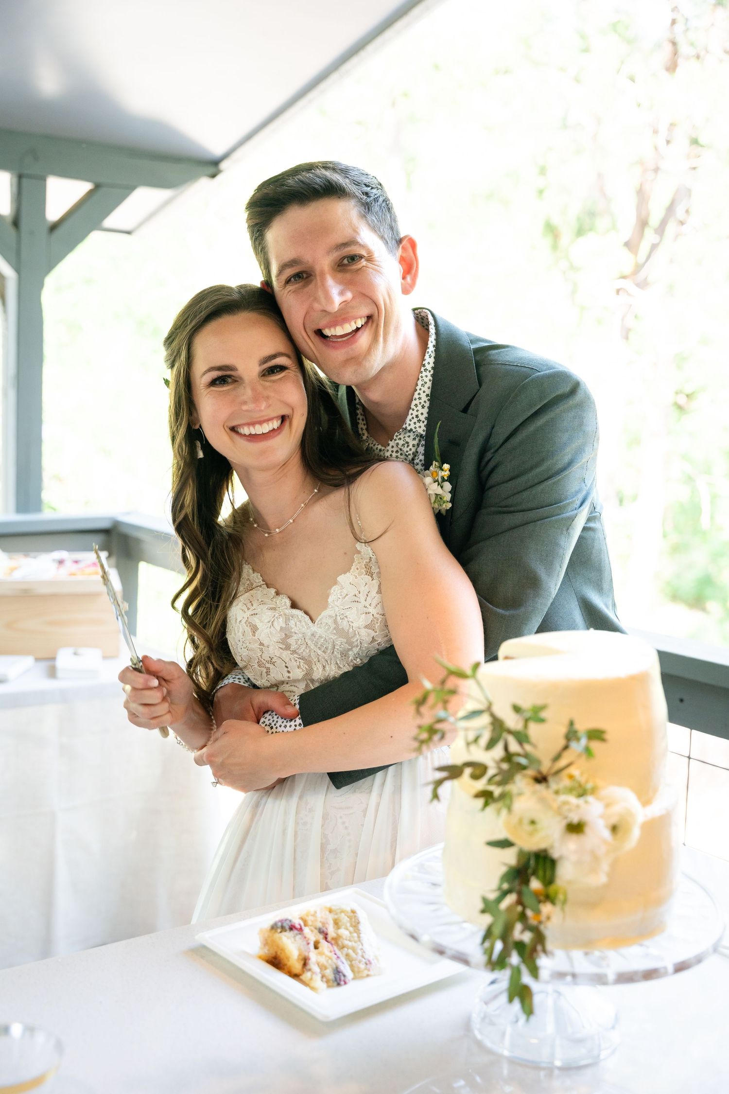 Romantic moment between newlyweds at reception table with wedding cake.