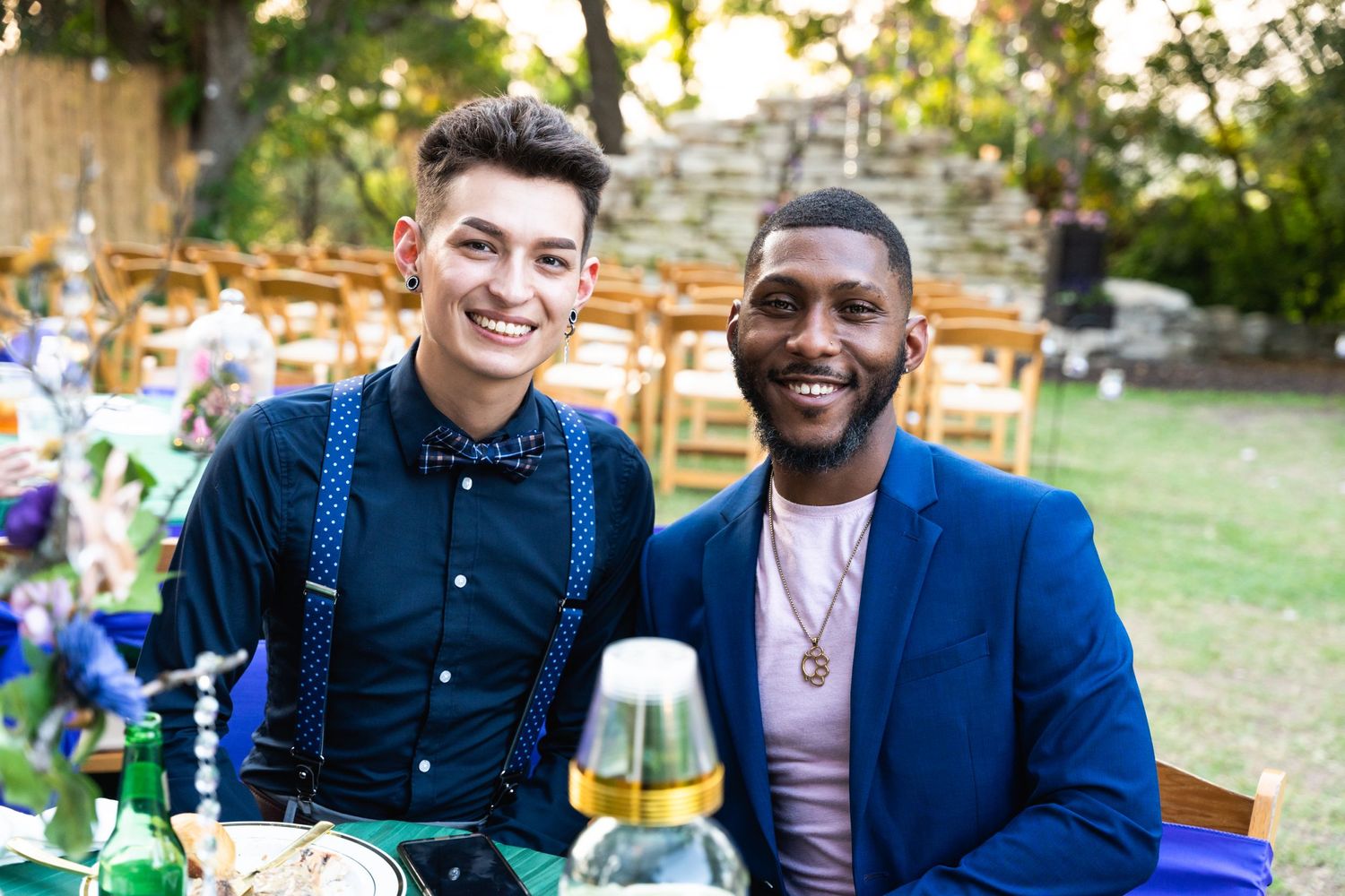 Two wedding guests smiling at an outdoor reception table.