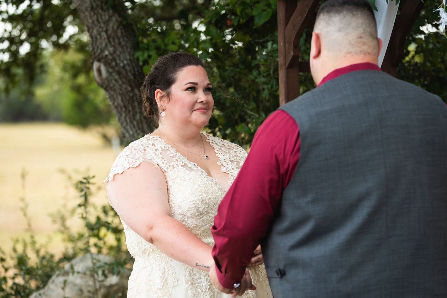 Intimate wedding ceremony moment captured in natural outdoor setting with sunlit background.