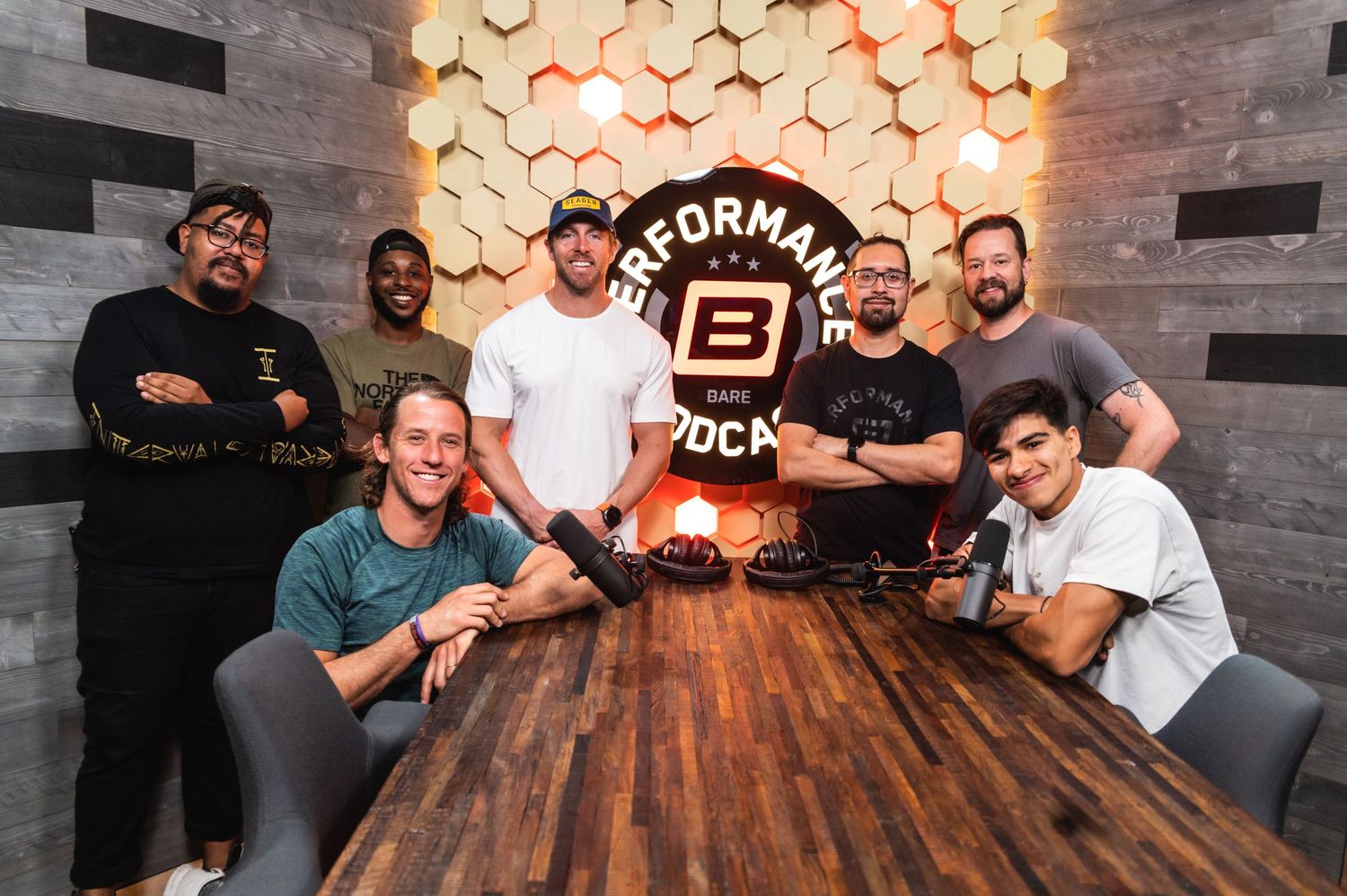 Team members gather around wooden table at Performance Block with illuminated wall decoration.