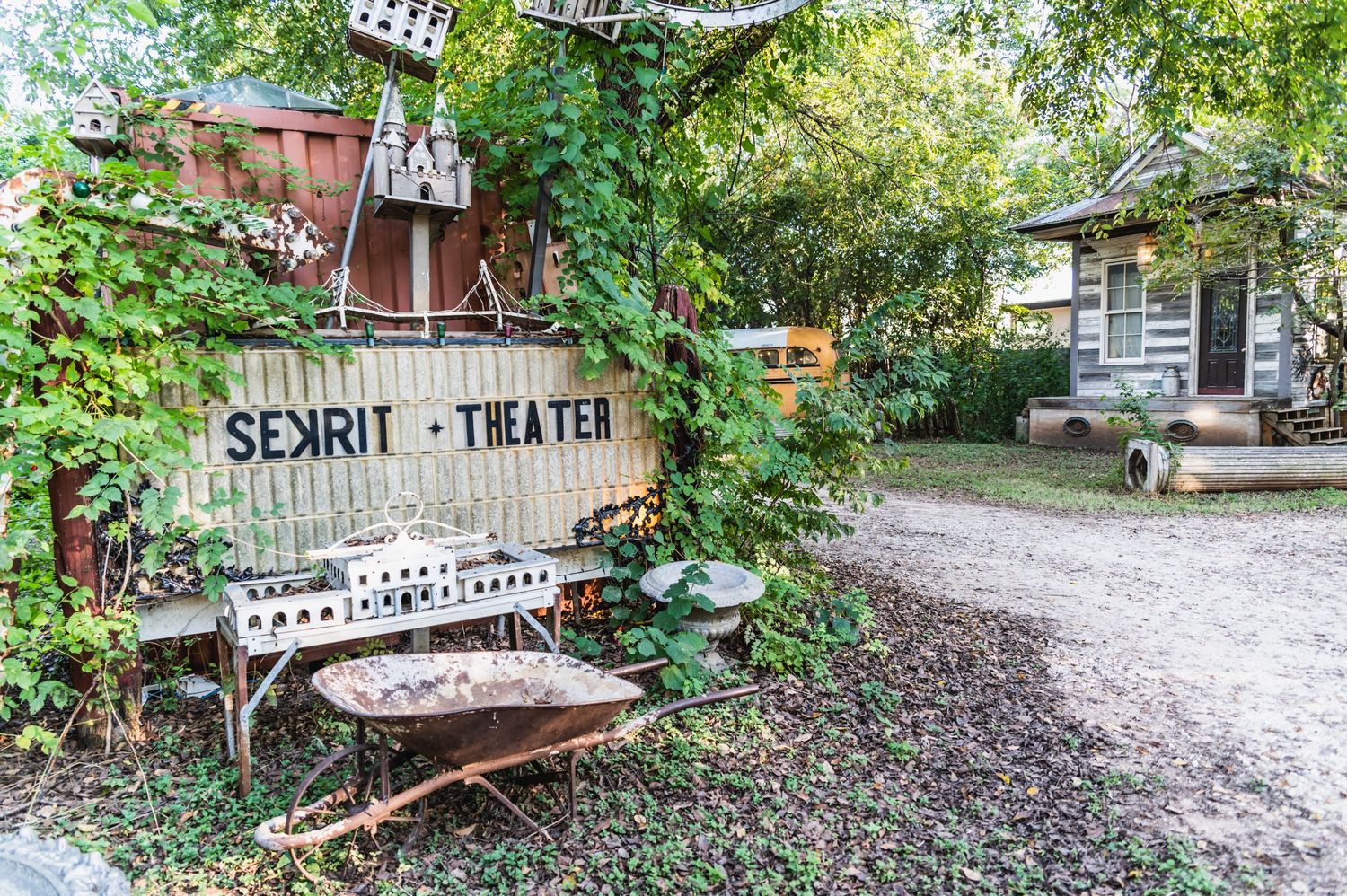 Rustic spirit theater sign with decorative bench in garden setting.