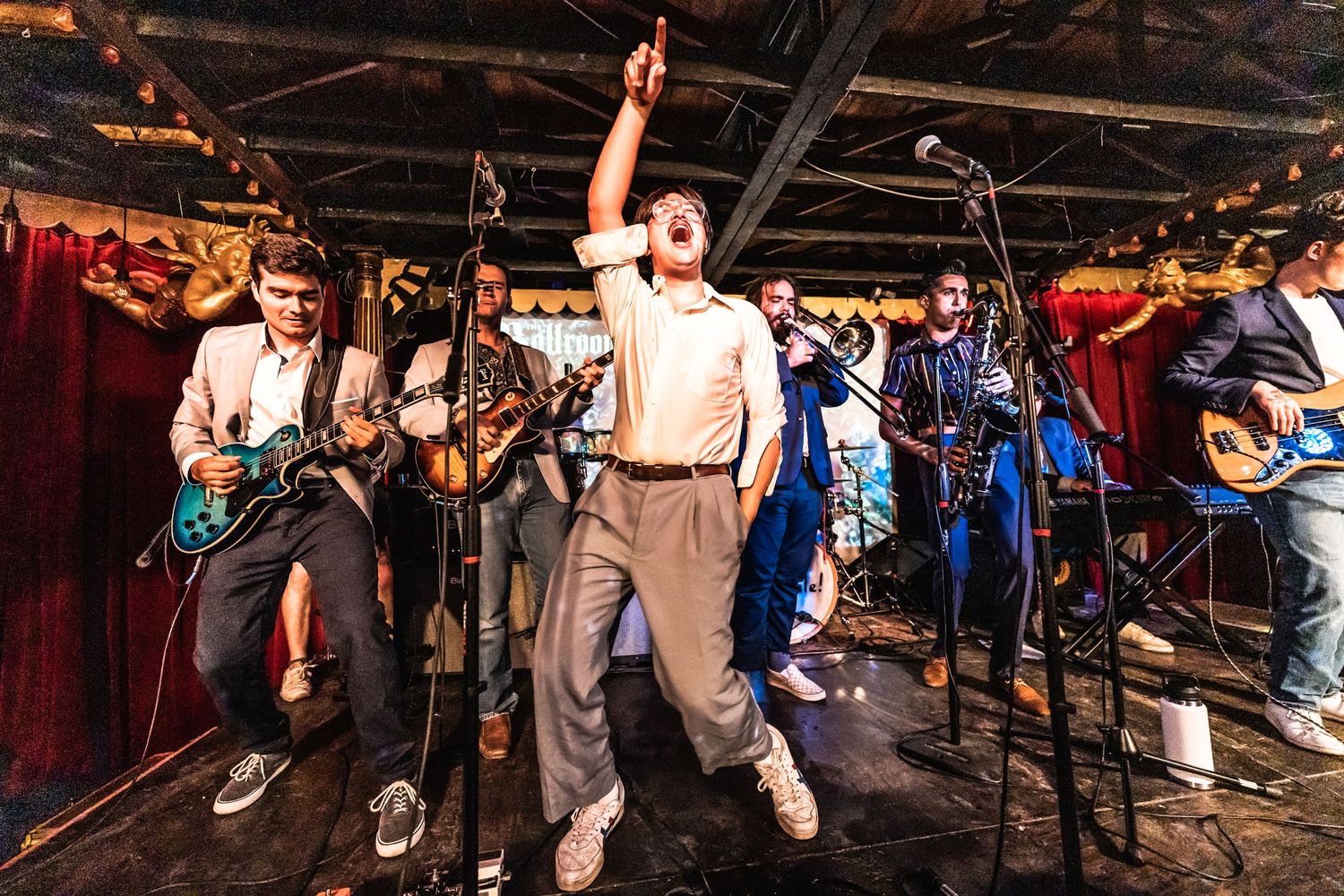 Musicians perform energetically on stage during a live concert performance.