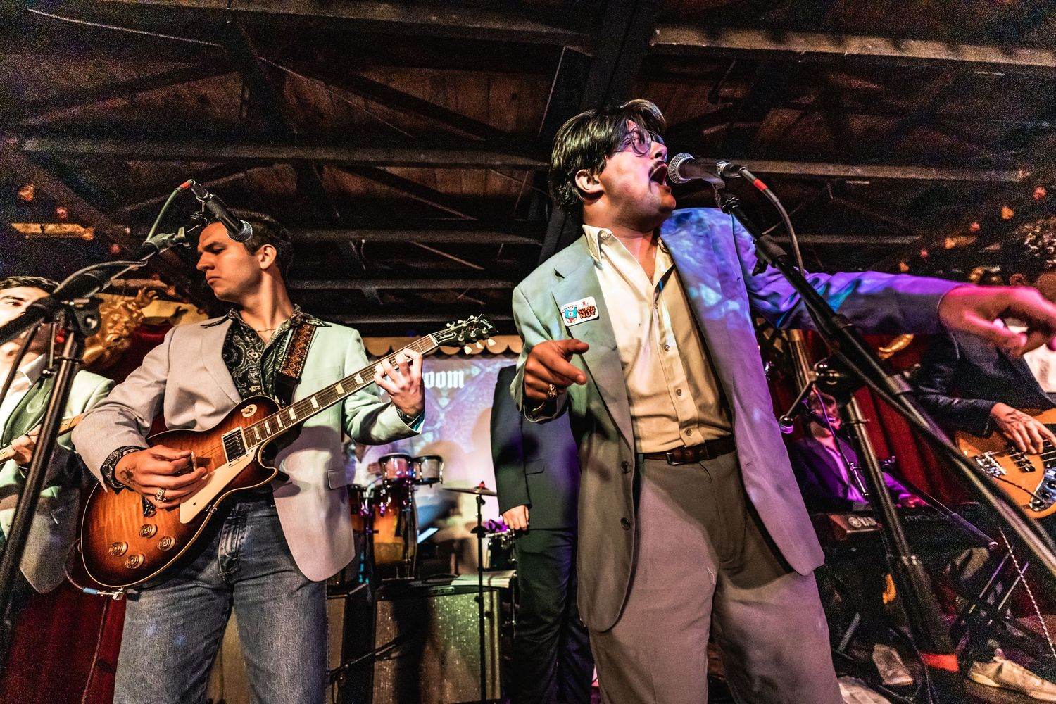 Musicians performing on stage with guitars under dramatic stage lighting.
