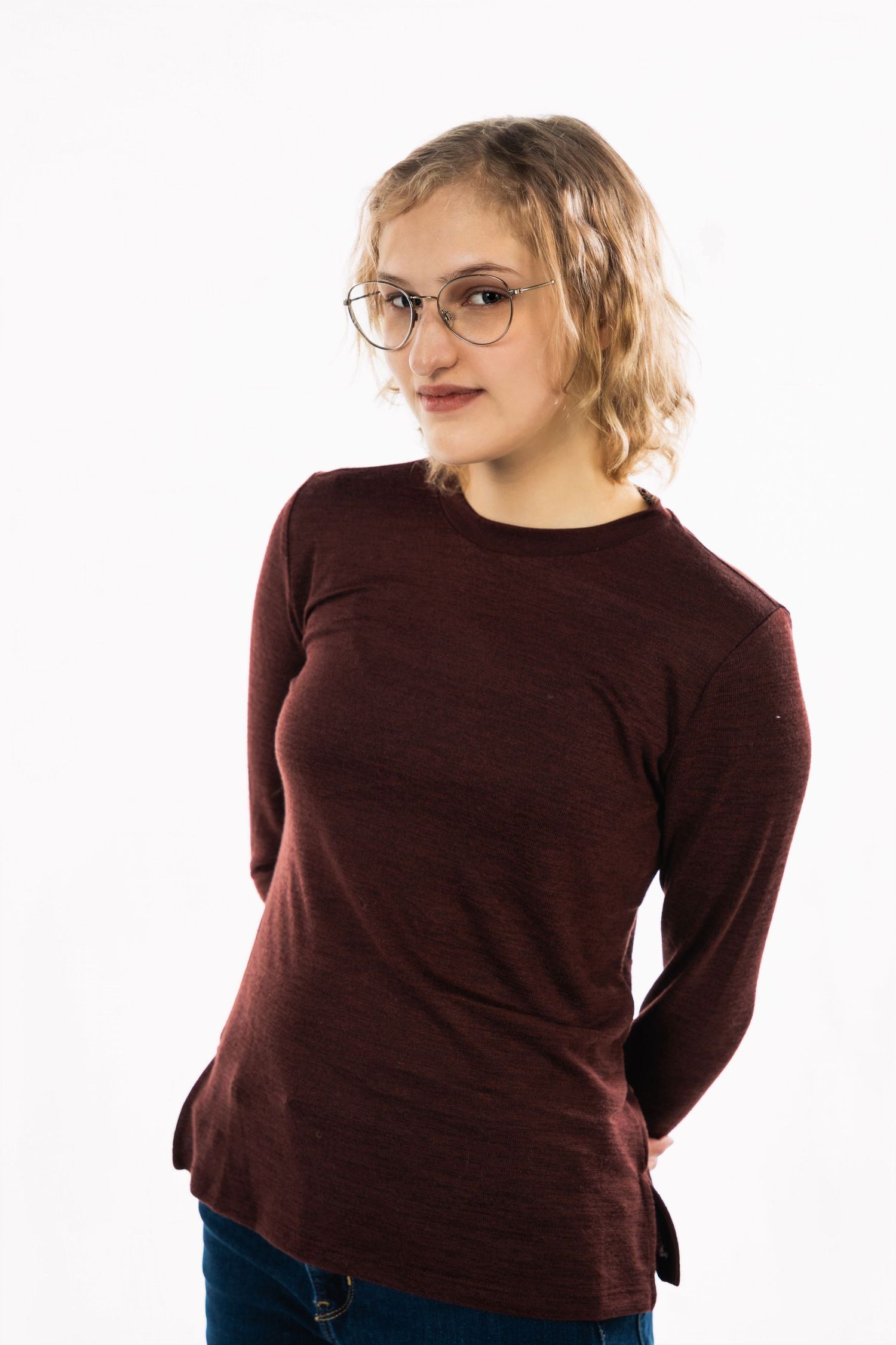 Studio portrait of person in maroon sweater and glasses against white backdrop.