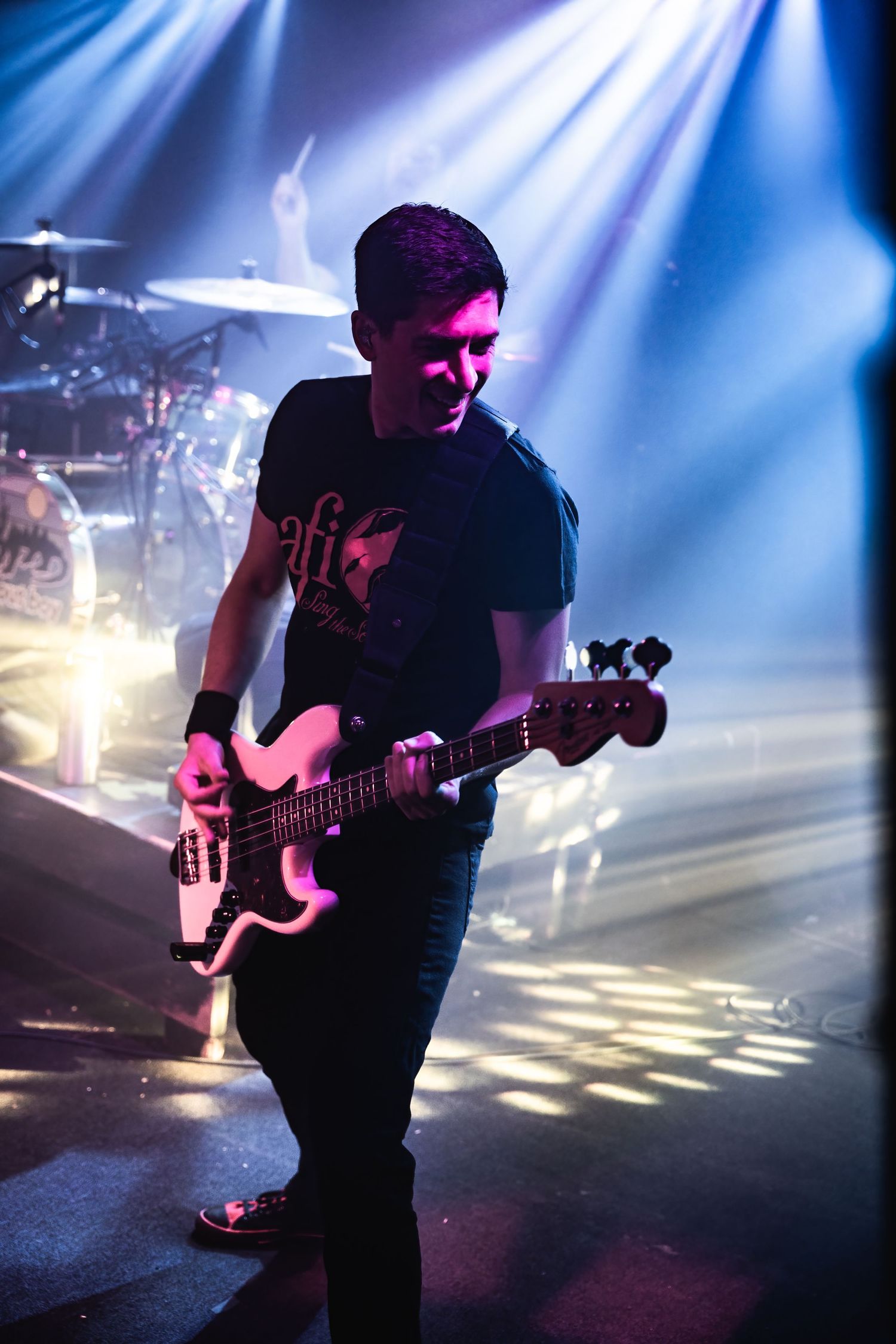 Bass player performing on stage with dramatic blue lighting and smoke effects.