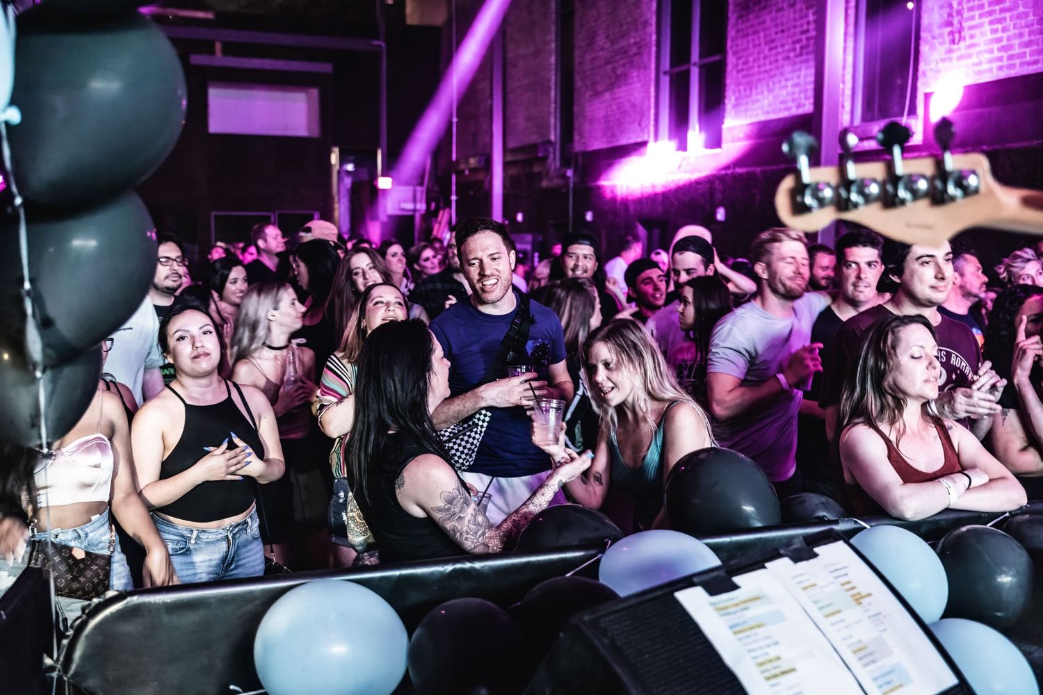 Concert audience fills venue with black balloons decorating the space during live performance.