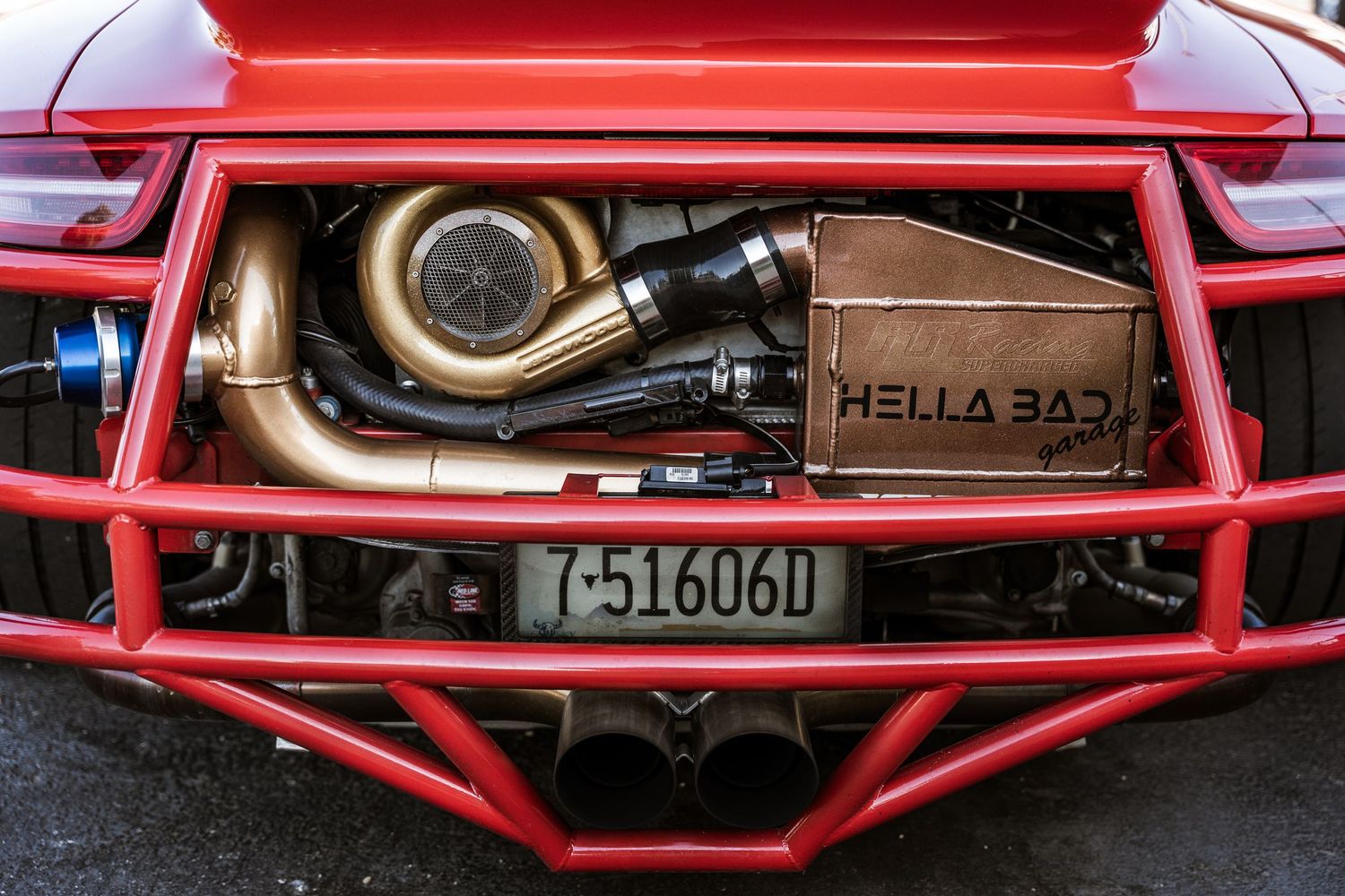 Engine bay detail showing performance exhaust components and Hella horns on a modified sports car.