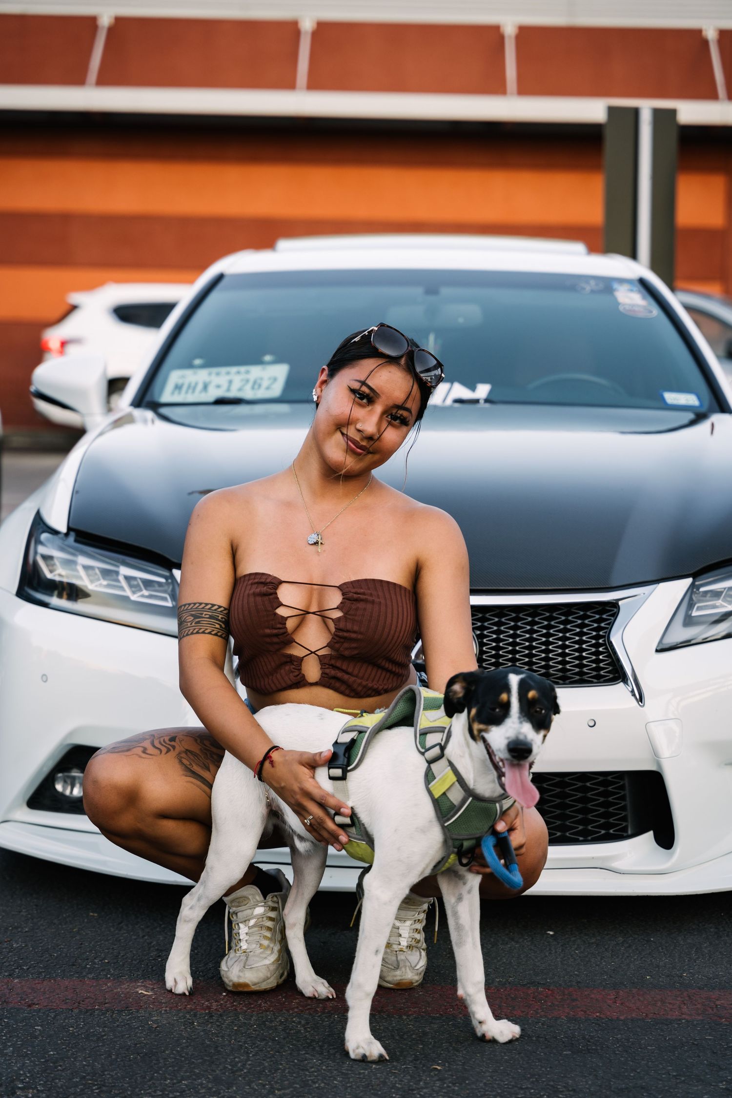 A person and their Jack Russell Terrier dog posing in front of a white Lexus.