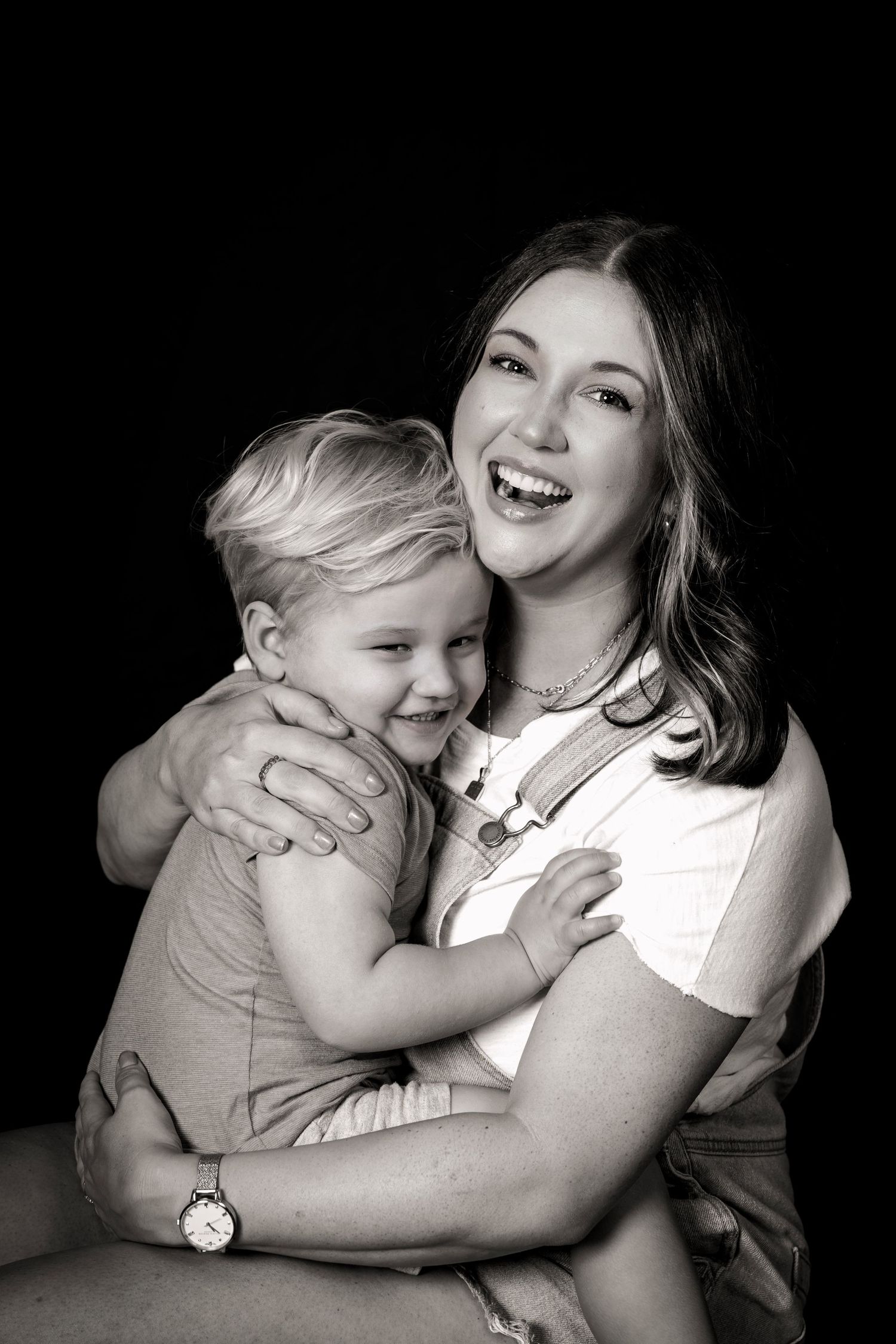 Black and white studio portrait capturing joyful moment between parent and toddler.