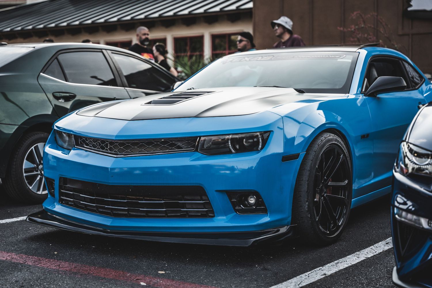 Bright blue Chevrolet Camaro SS with black wheels and custom front splitter in a parking lot.