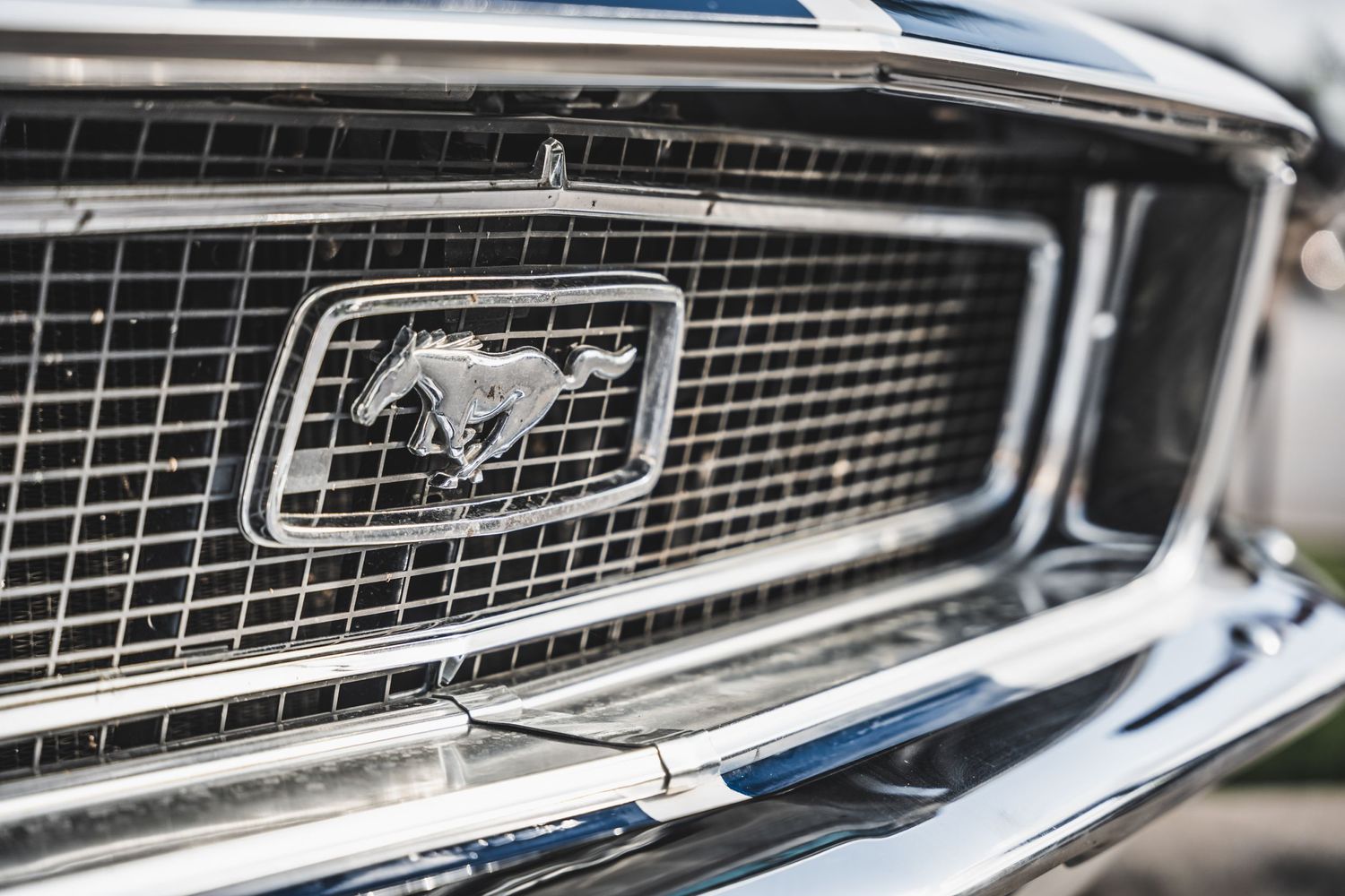 Close-up of classic Ford Mustang grille with iconic running horse emblem in chrome.