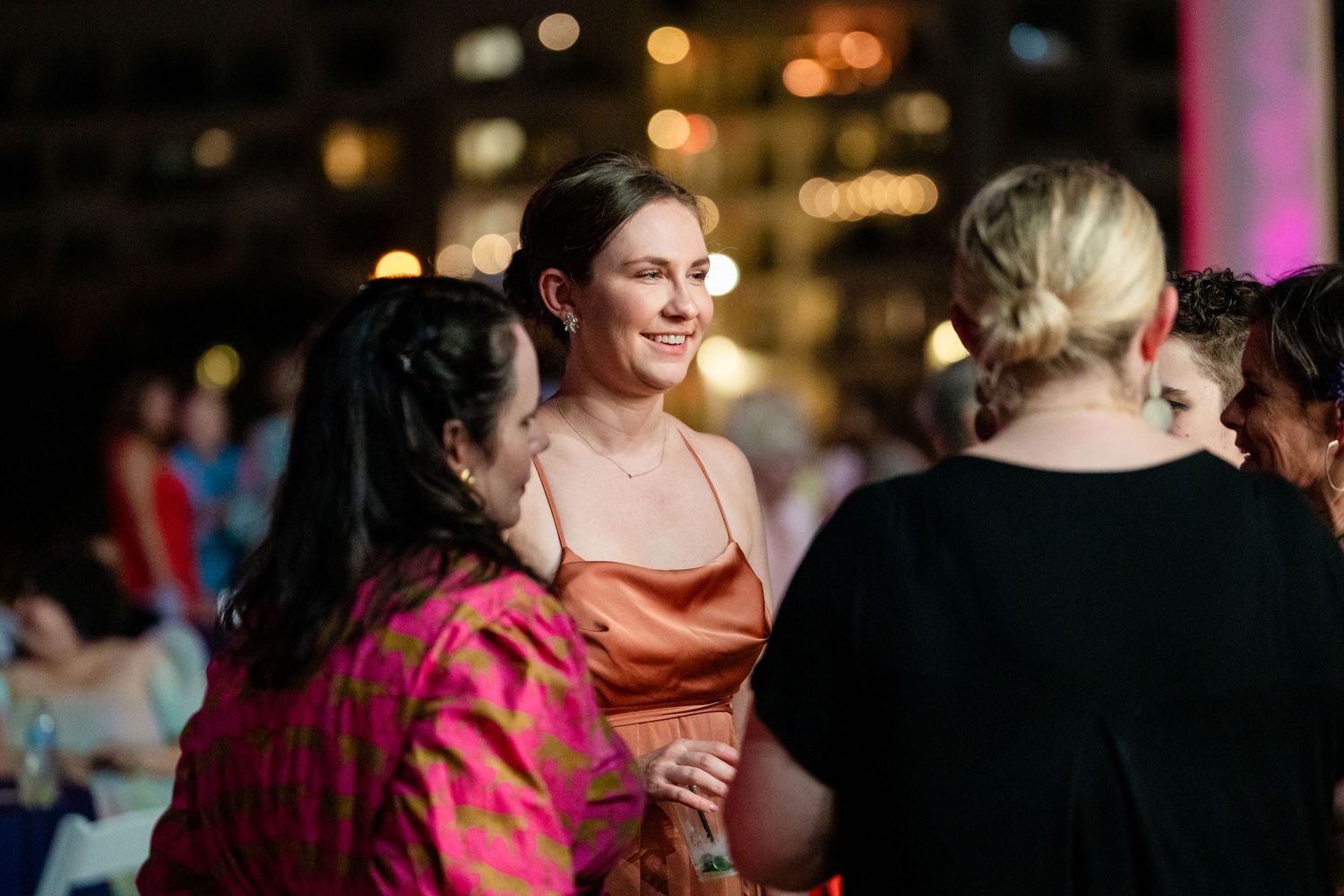People socializing and dancing at an evening event with warm ambient lighting.