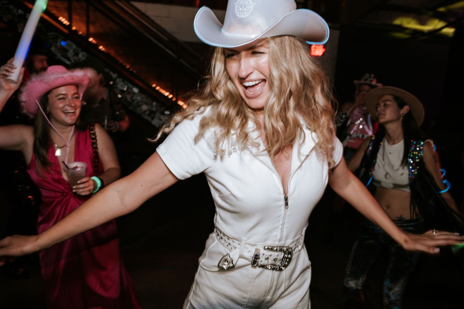 A person in western attire dances joyfully at a country-themed celebration.