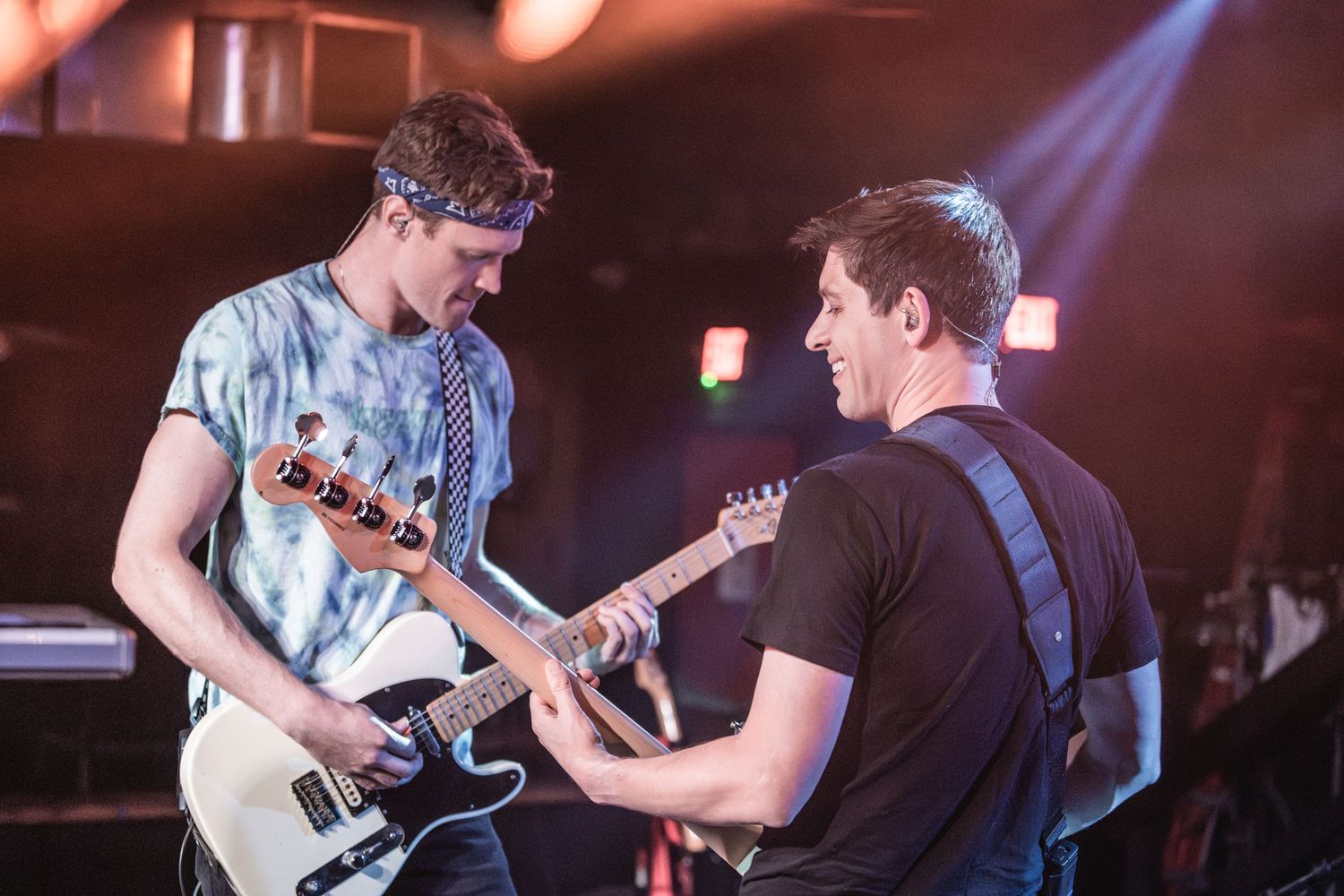 Musicians performing together on stage with dramatic blue concert lighting.