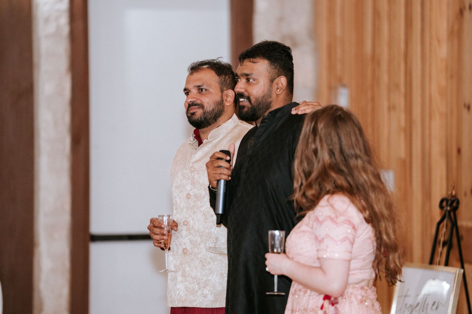 Three people enjoying drinks and conversation at an elegant indoor celebration.