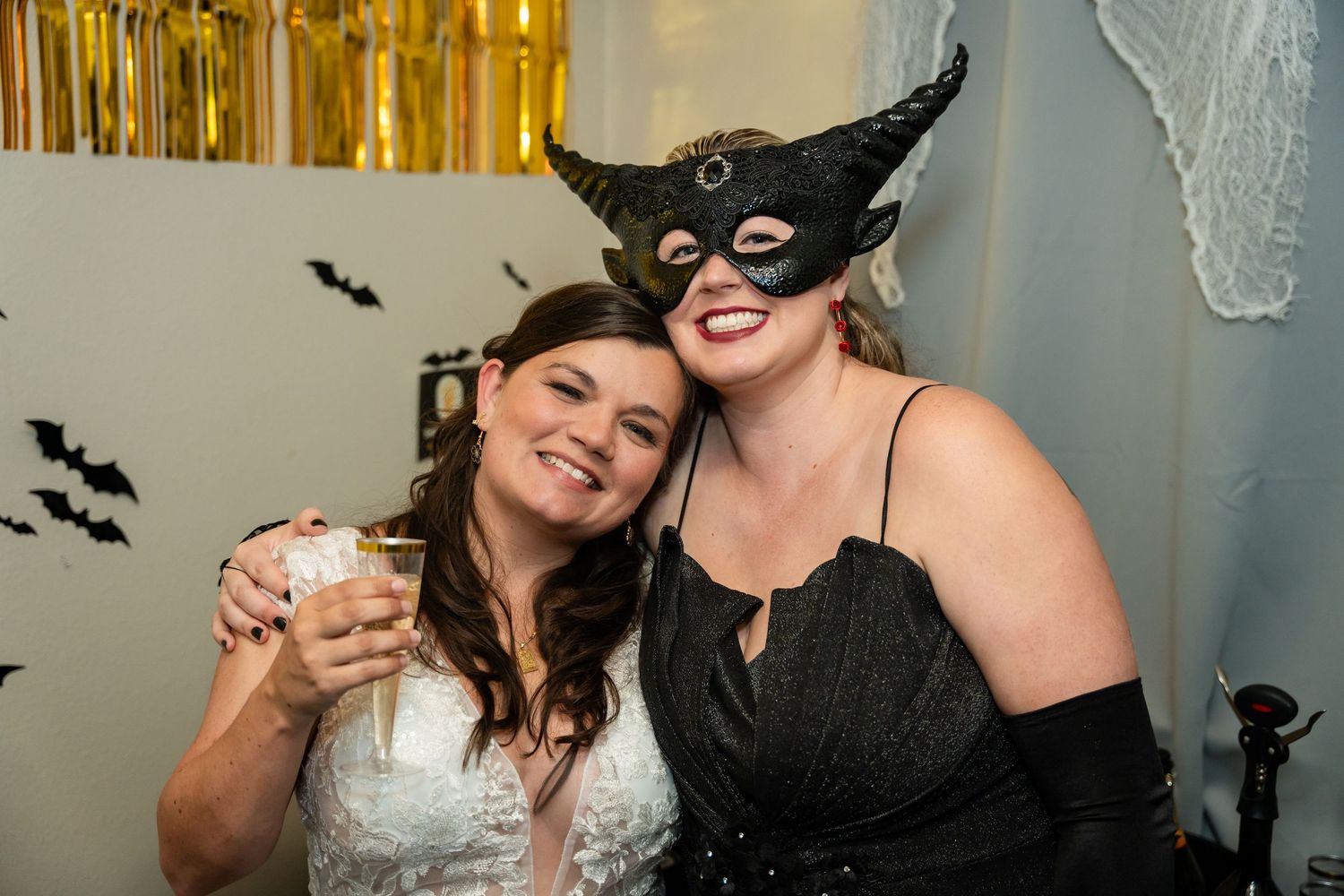 Wedding celebration with Halloween themed masks and decorations at an indoor party.