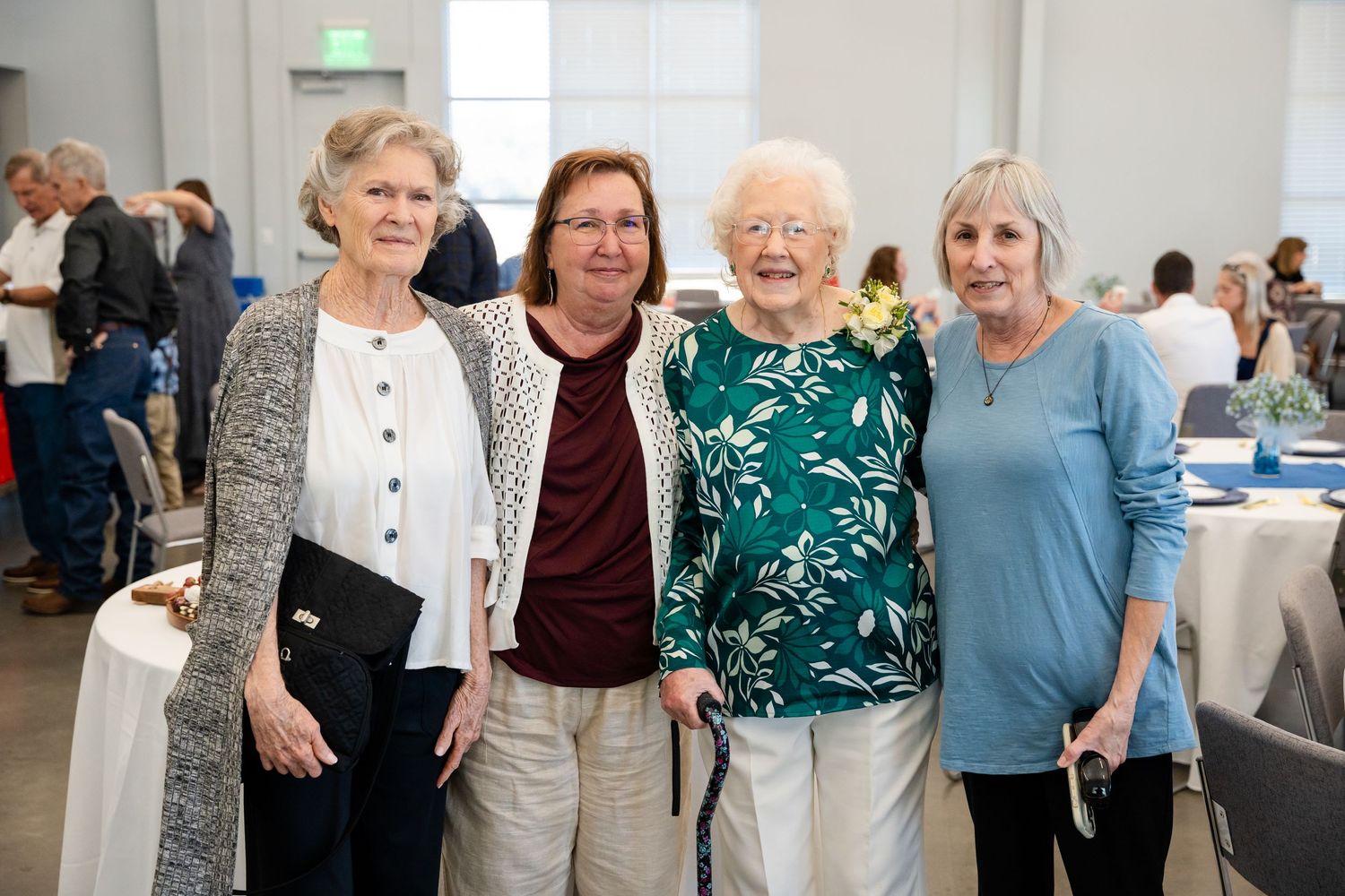 A group of women in casual attire gather together at an indoor social event.