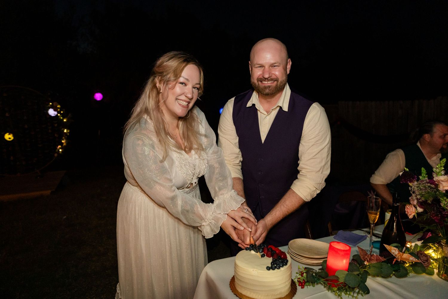 Newlyweds cut their wedding cake together during evening reception.