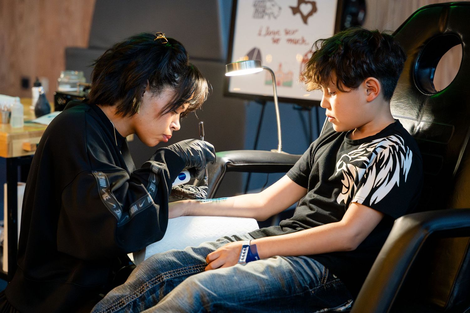 A tattoo artist carefully works on creating a tattoo for a client seated in a professional studio chair.
