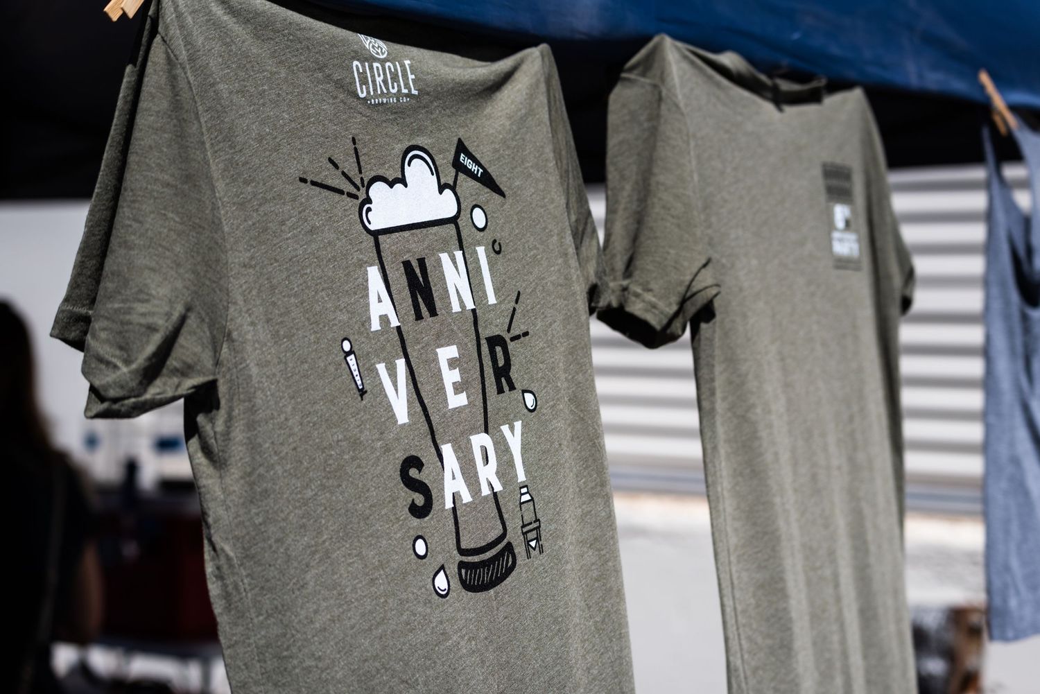 Gray t-shirts with graphic designs hanging on display at an outdoor market.
