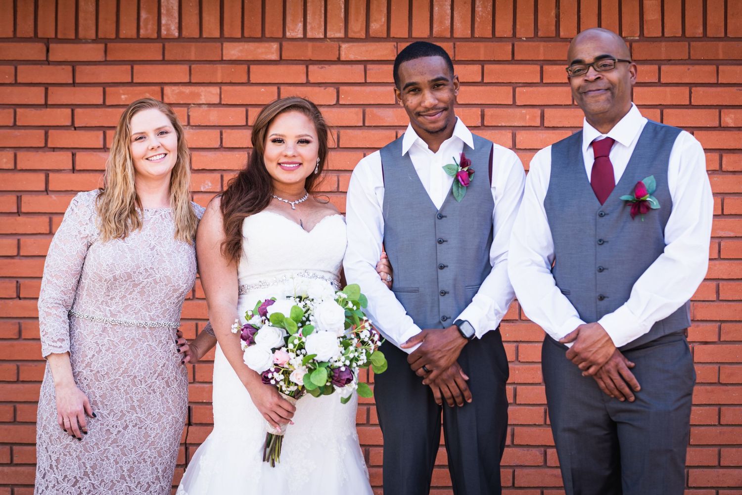 Wedding party poses against a brick wall backdrop at the ceremony.