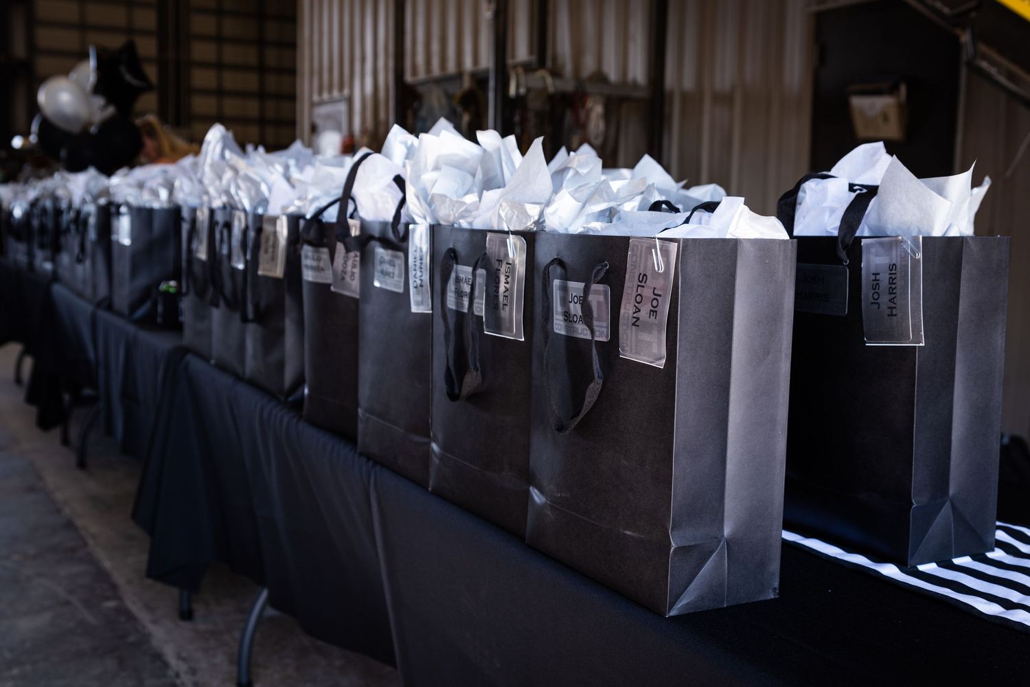 Row of elegant black gift bags with tissue paper at a formal event.