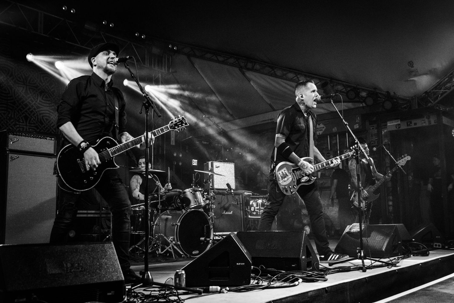Black and white shot of band performing on stage with dramatic backlighting.