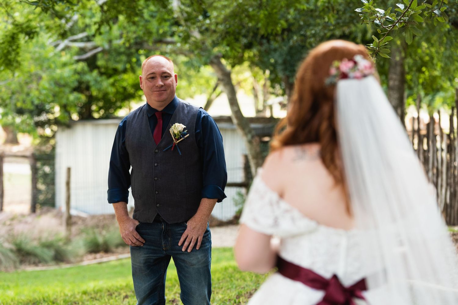 Garden wedding scene with casual groom's attire against green foliage.