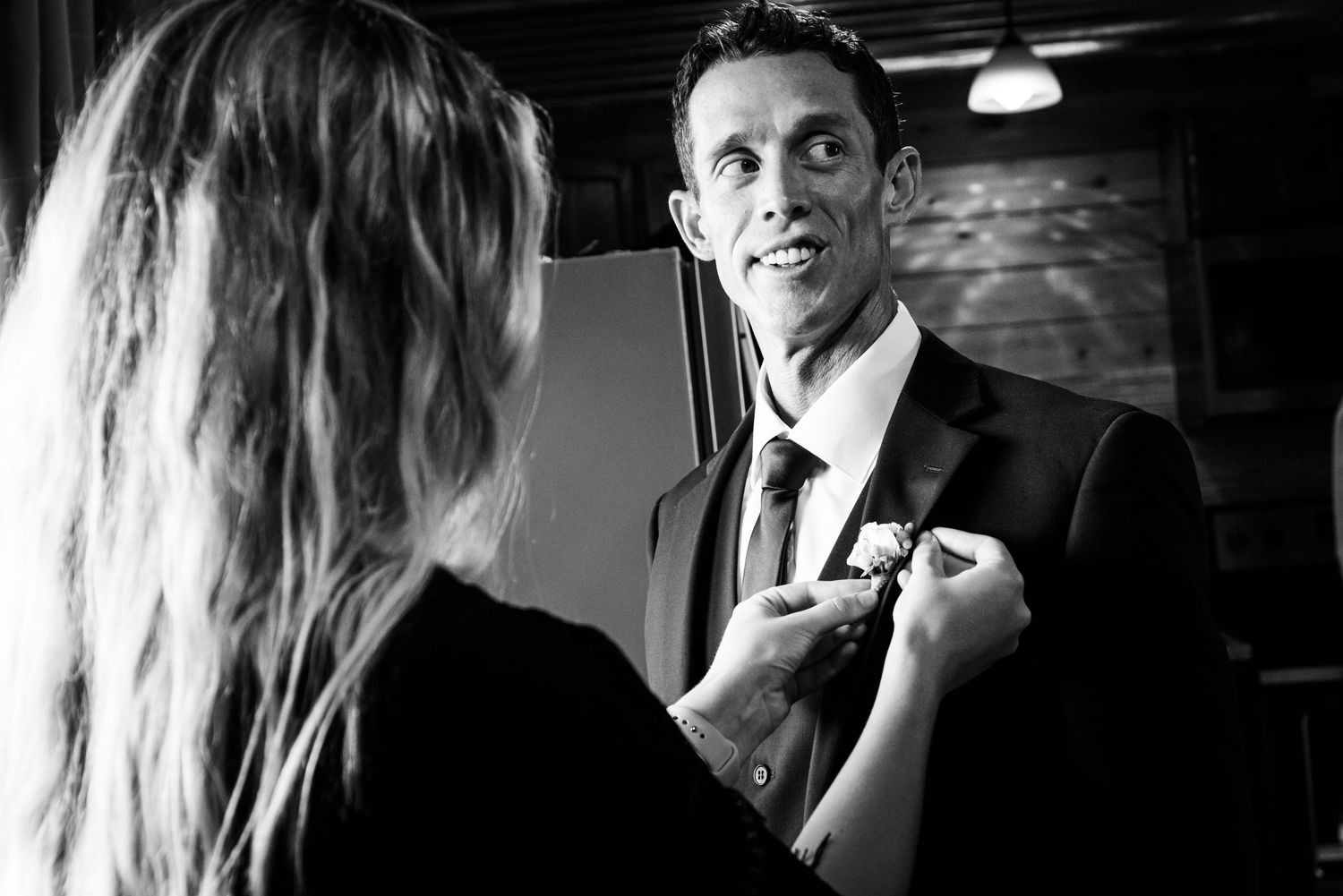 Black and white candid photo of pre-wedding preparations in a dimly lit room.