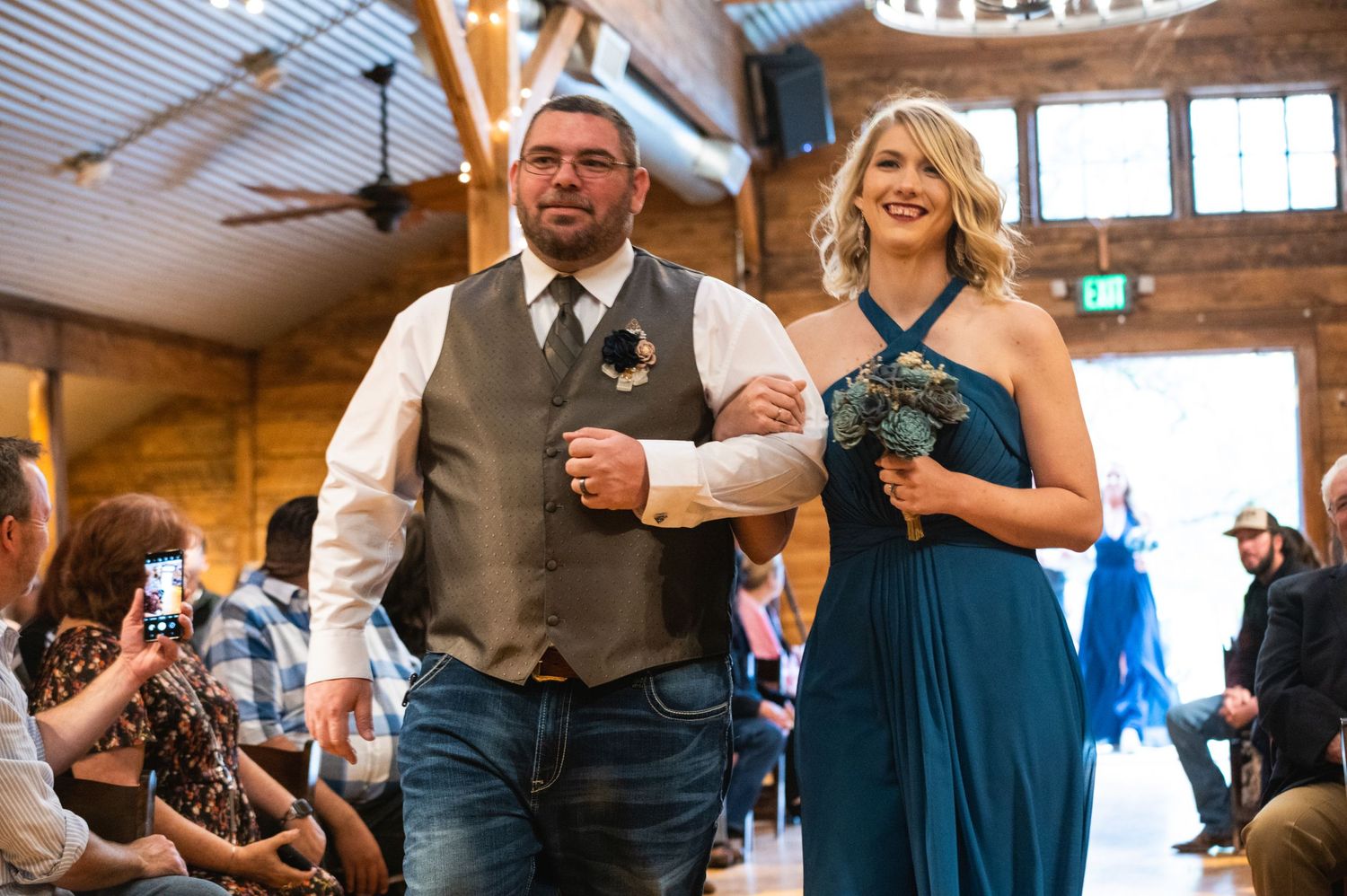 A couple walking down the aisle at a wedding ceremony in a wooden barn venue.