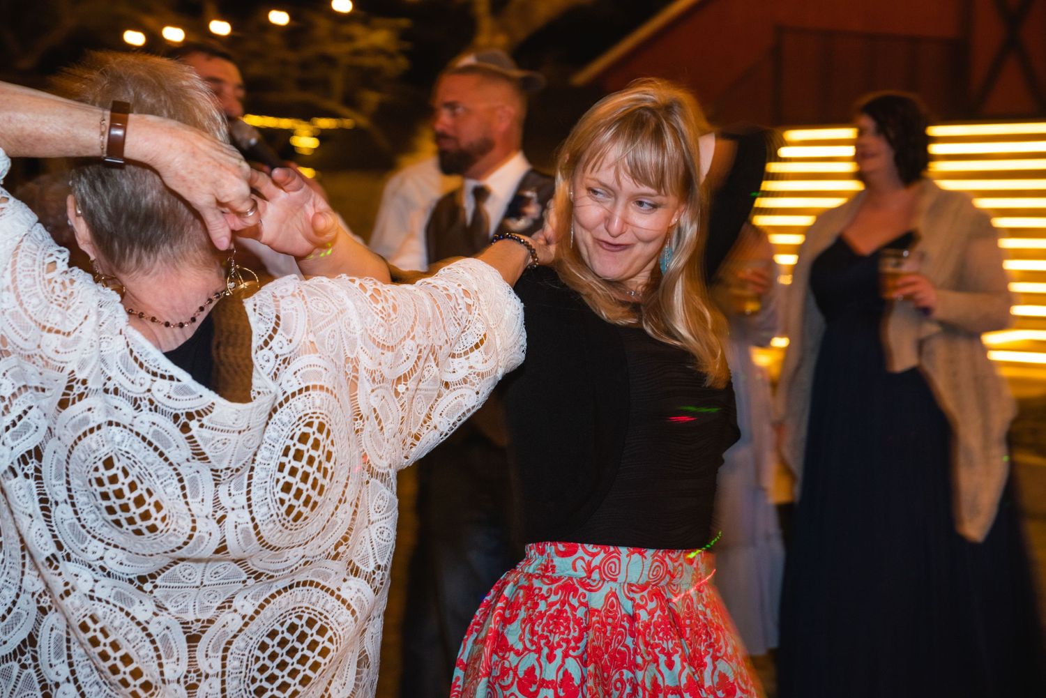 Wedding guests dancing and laughing together on a lively dance floor.